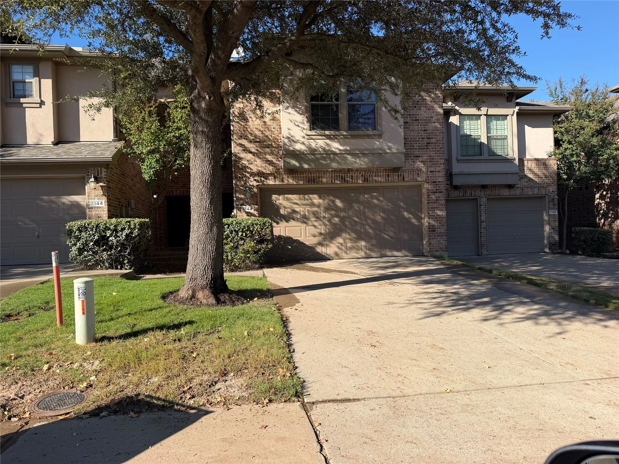 Brick and stucco exterior with multiple garage bays, concrete driveway, and mature landscaping