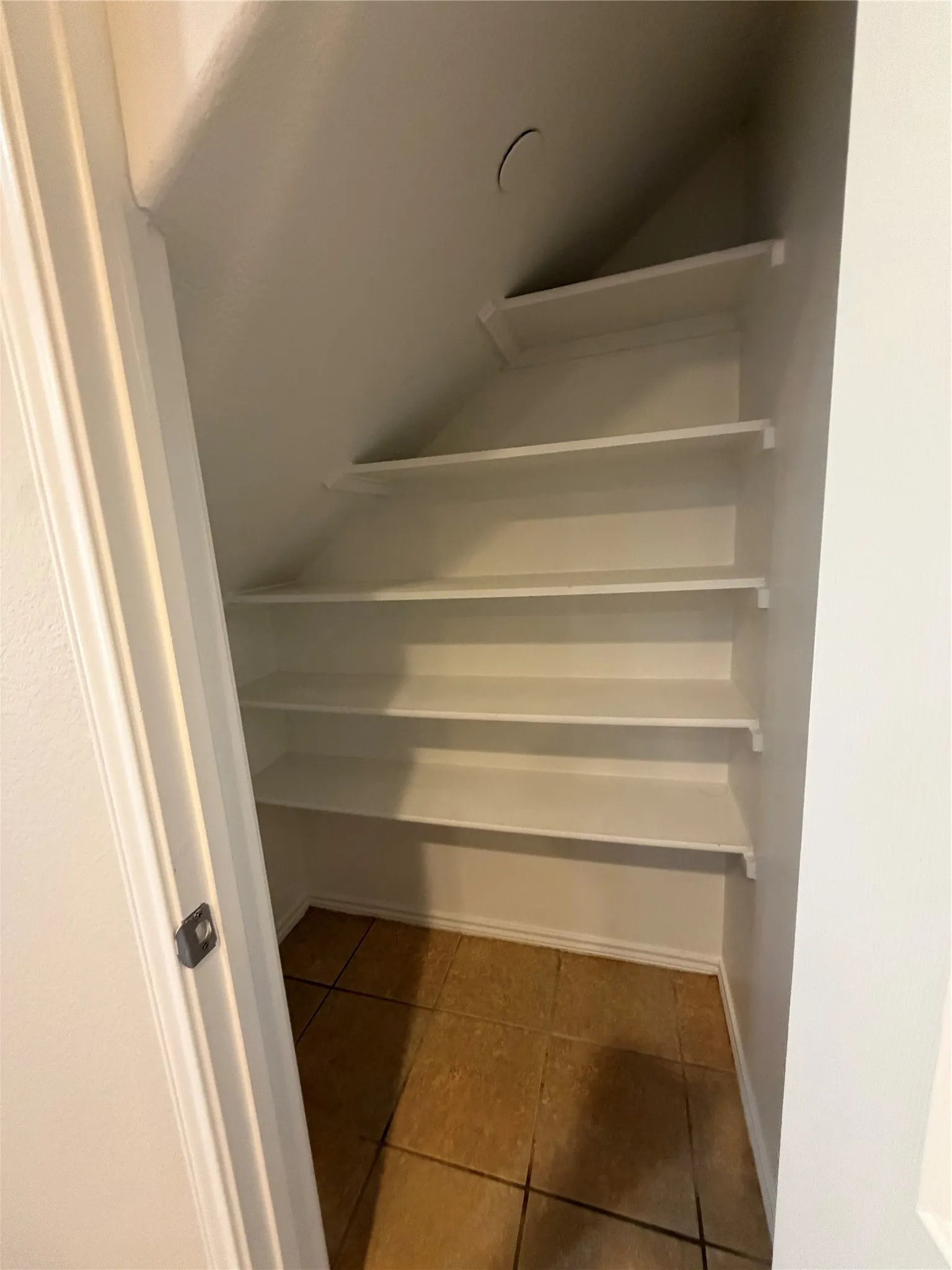 Built-in shelving with multiple levels, sloped ceiling, and tiled flooring