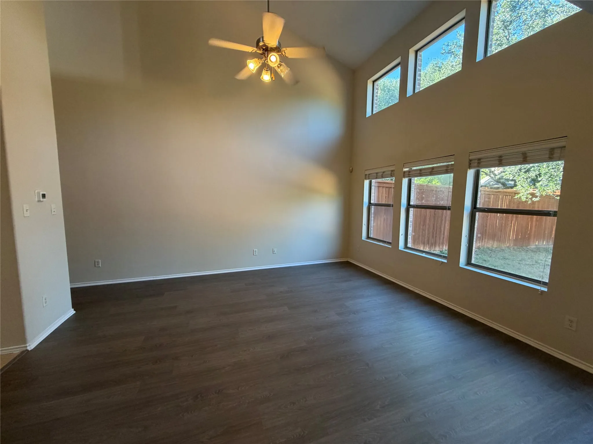 Vaulted ceiling, wood-finish flooring, ceiling fan, and multiple windows