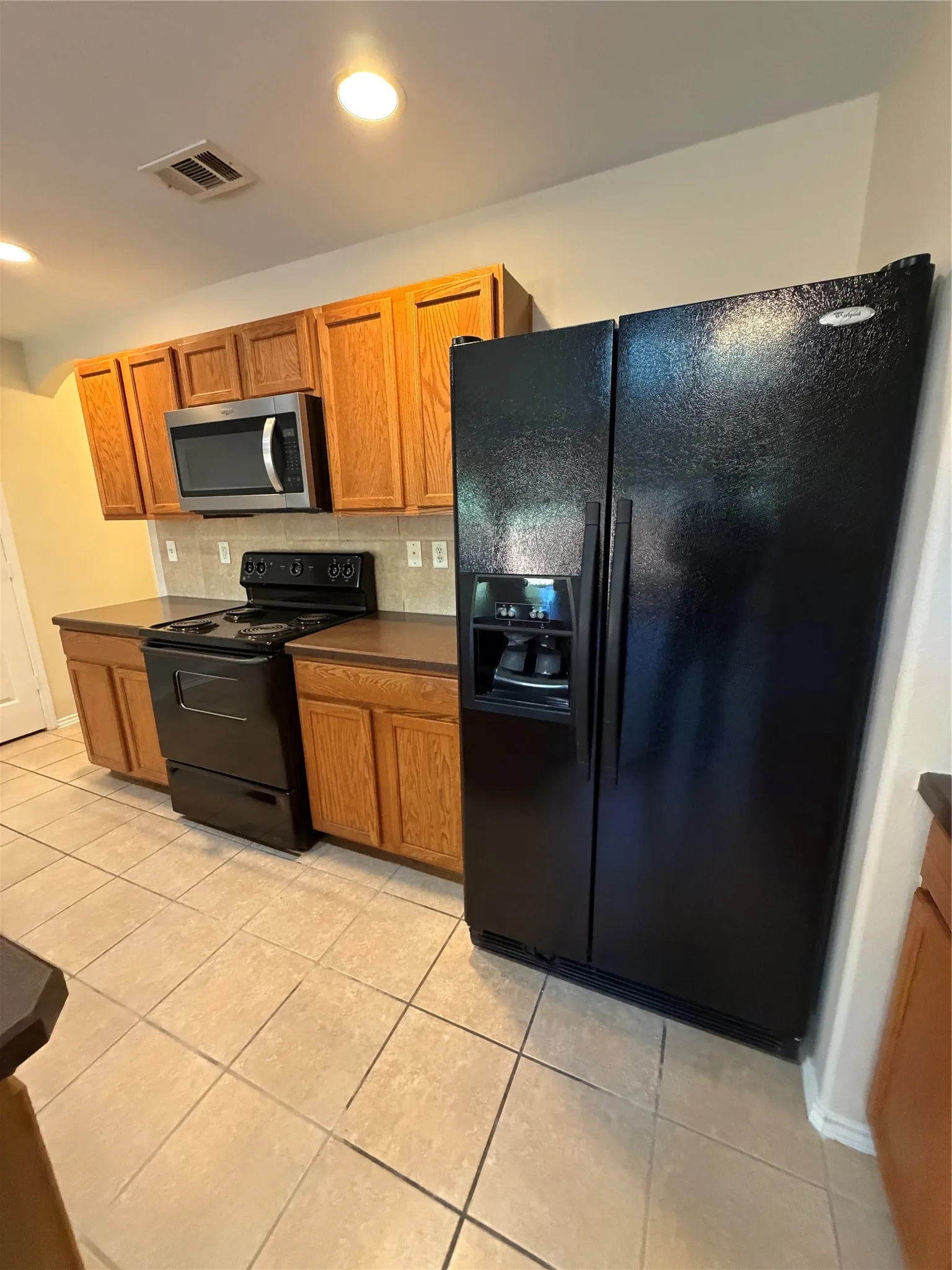 Kitchen featuring a side-by-side refrigerator, built-in microwave, electric range, and tile flooring