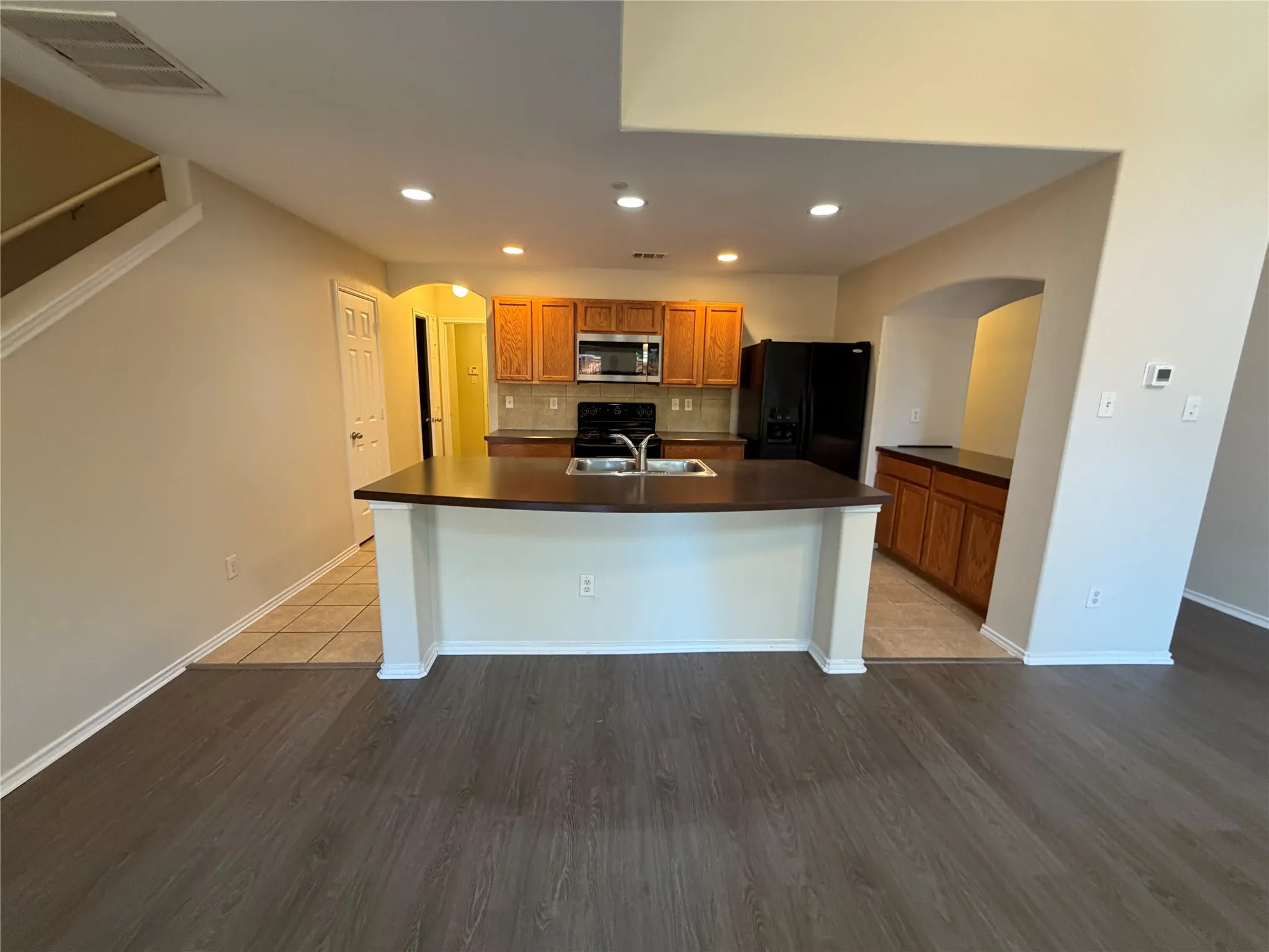 Kitchen with wood-finish cabinetry, built-in microwave, and black appliances
