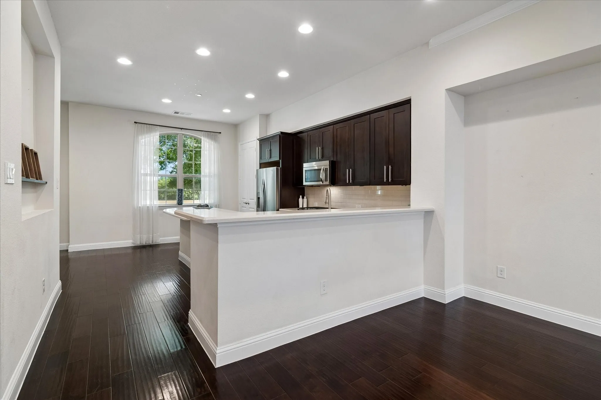 Dark wood-finish flooring with white baseboards throughout