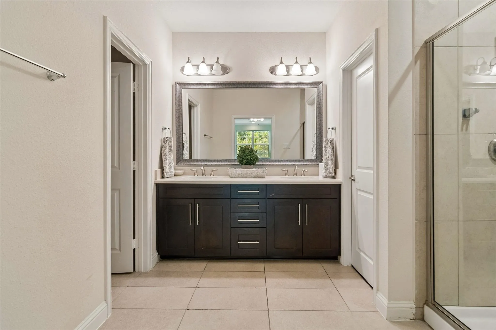 Dual vanity with undermount sinks, an ornate framed mirror, and two three-light sconces