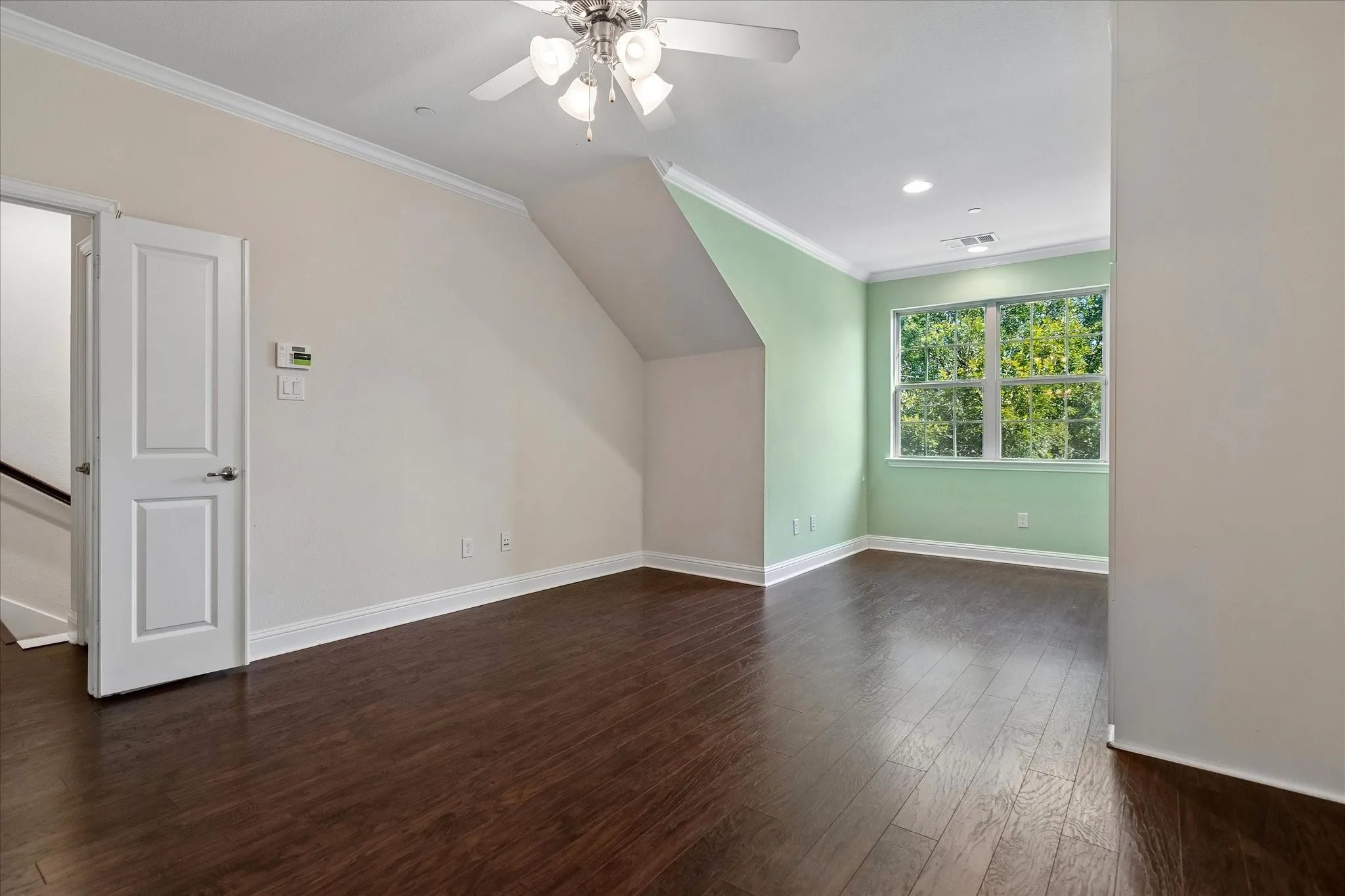 Hardwood-finish flooring, ceiling fan with light fixture, recessed lighting, crown molding, and window with exterior landscaping