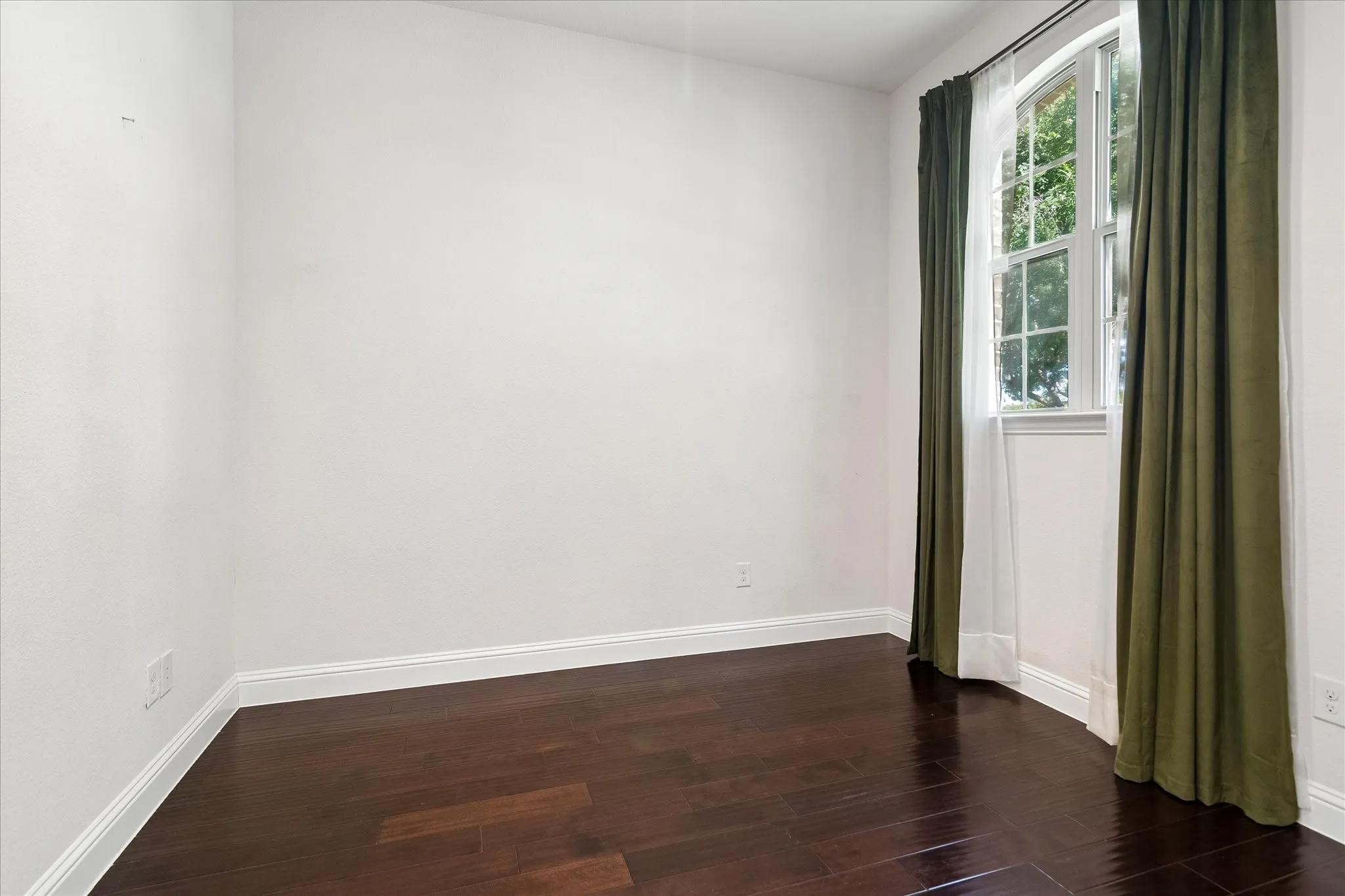 Wood-finish flooring, white wall finishes, and a window with natural light
