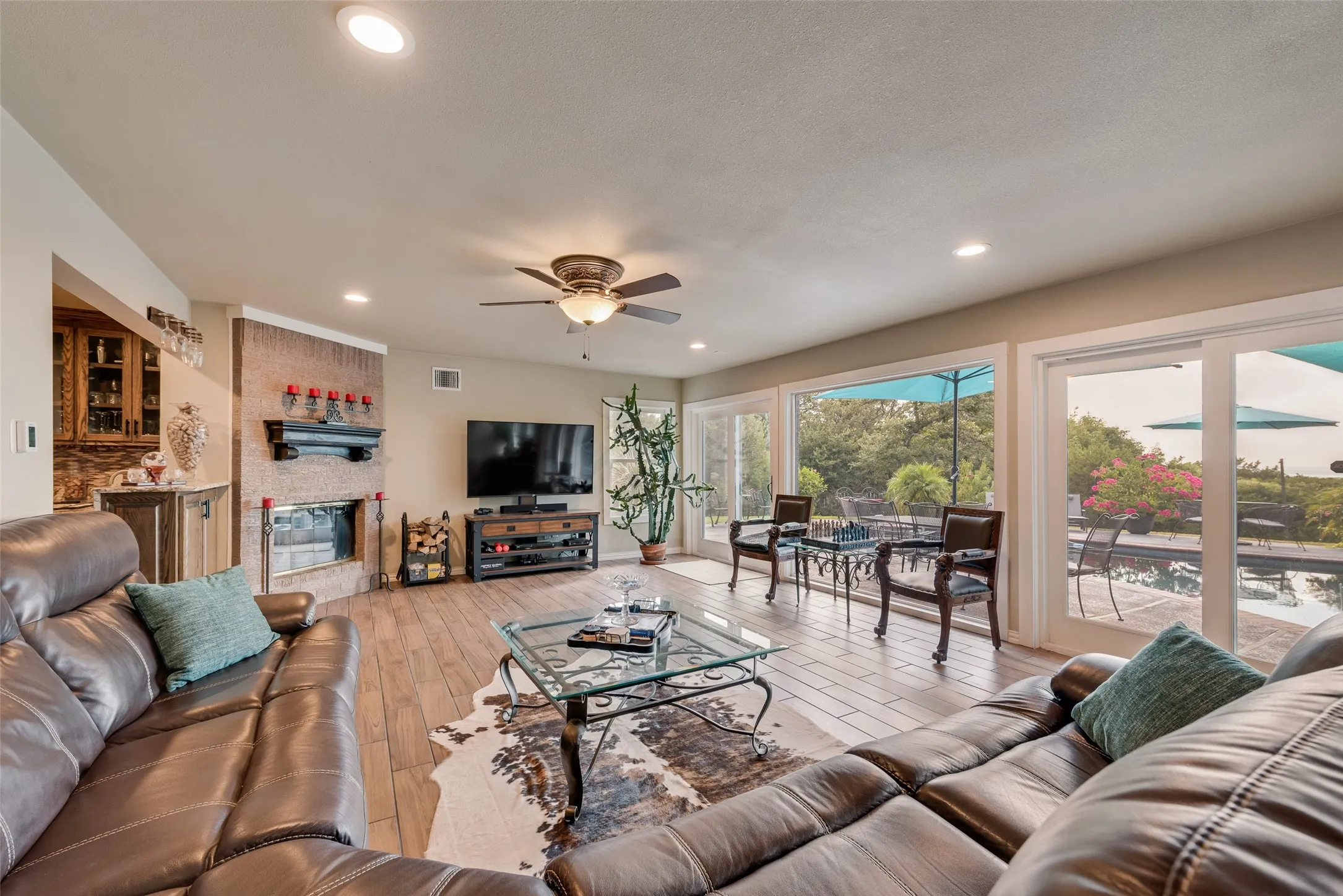 Spacious living area featuring wood-finish flooring, a stone-clad fireplace, and recessed lighting