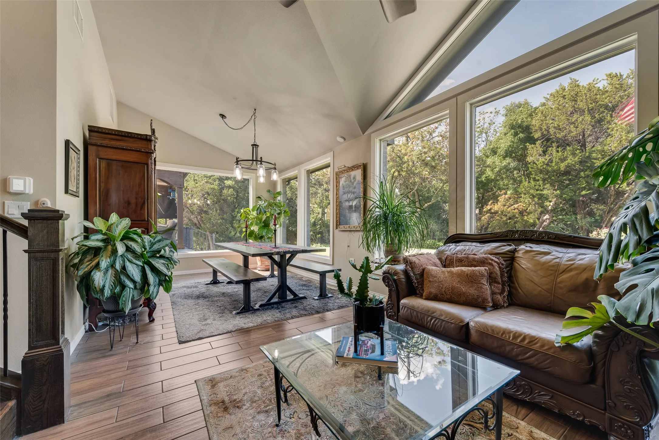 Vaulted ceiling, wood-finish flooring, ample natural light from large windows, and a black metal chandelier