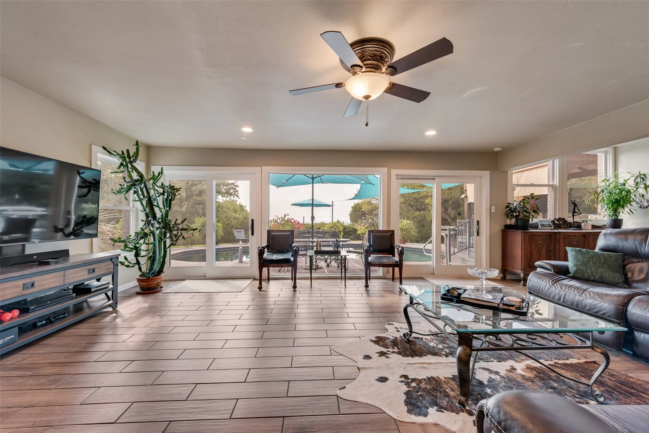 Wood-finish flooring throughout, ceiling fan, recessed lighting, and multiple sliding glass doors to the outdoor area