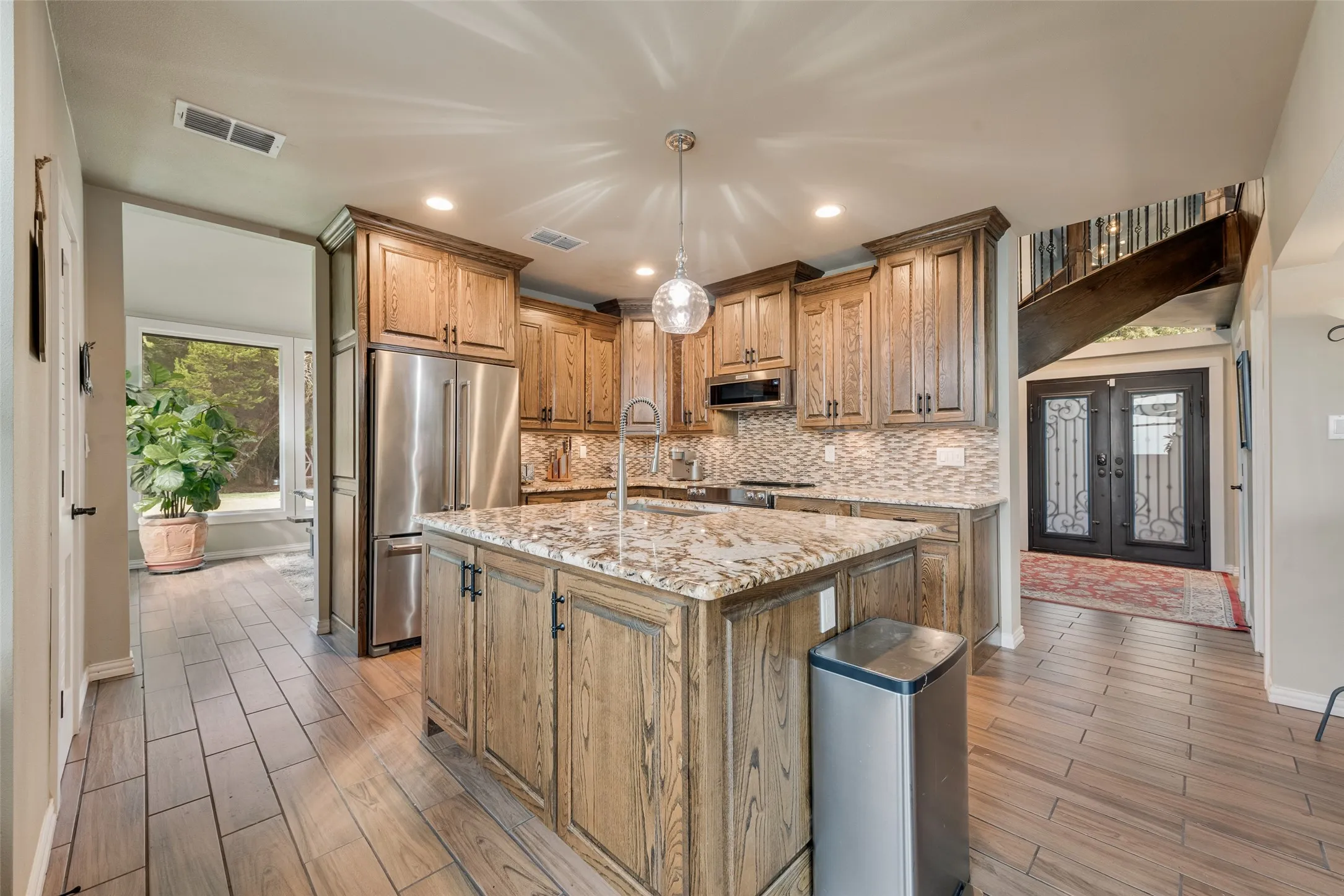 Kitchen featuring wood-finish cabinetry, stone countertops, stainless steel appliances, and a tiled backsplash