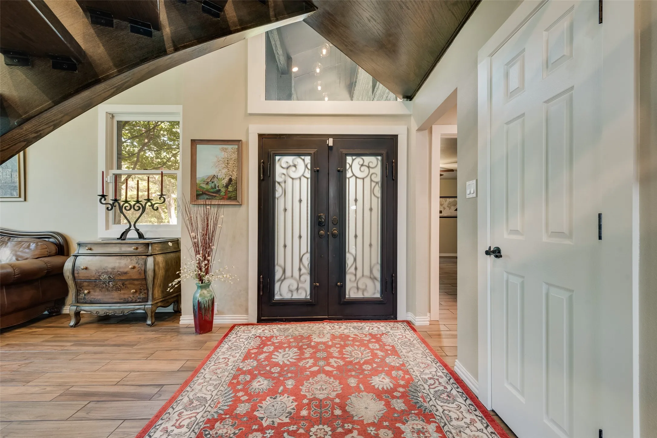 Double entry doors with decorative ironwork, wood-finish flooring, and a multi-pane window
