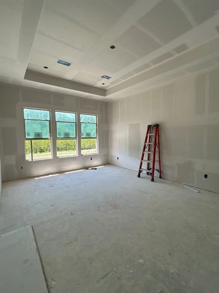 Tray ceiling with recessed lighting, multiple windows providing natural illumination, and unfinished walls ready for customization