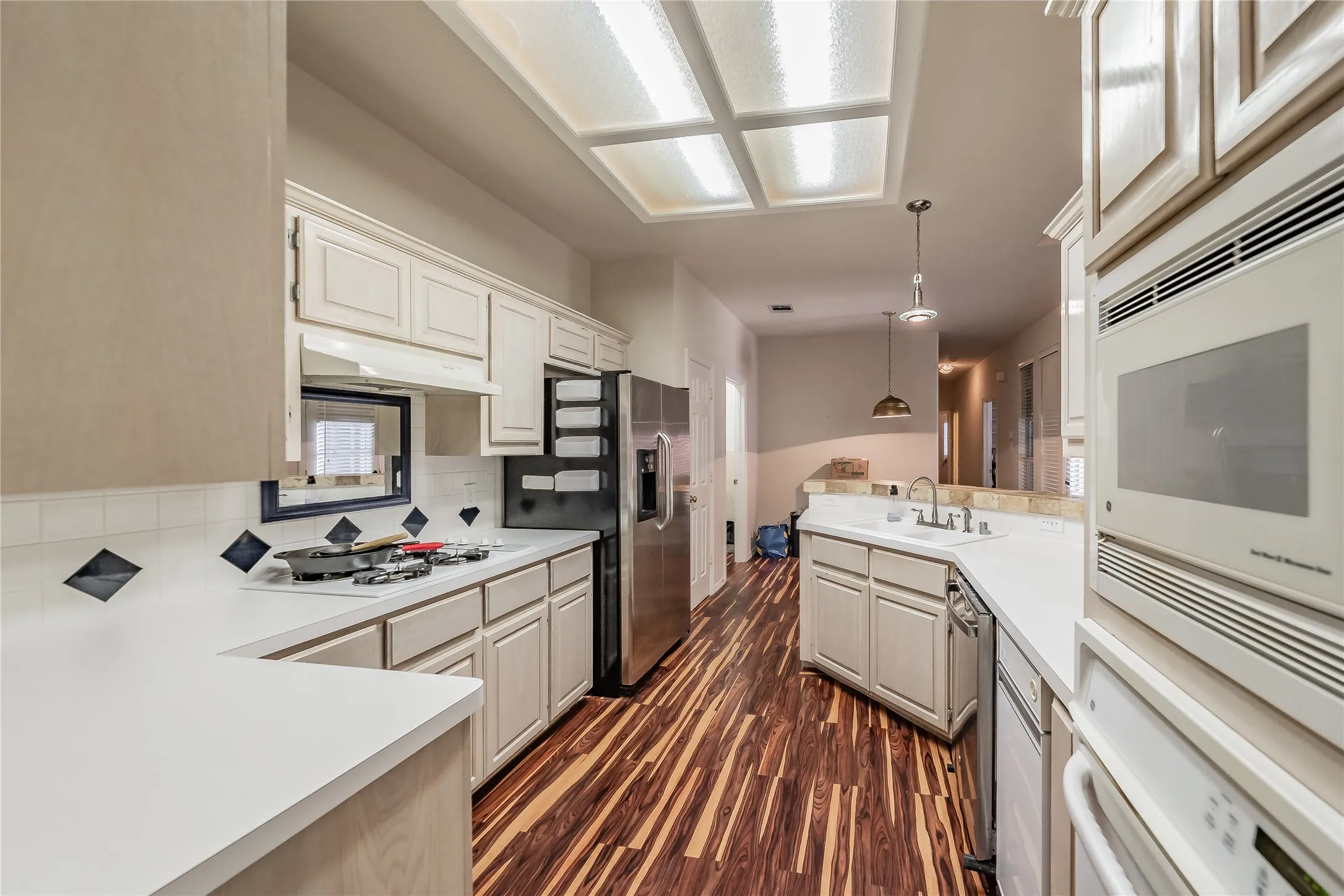 Kitchen featuring wood-finish flooring, white cabinetry, a built-in oven, and a built-in microwave