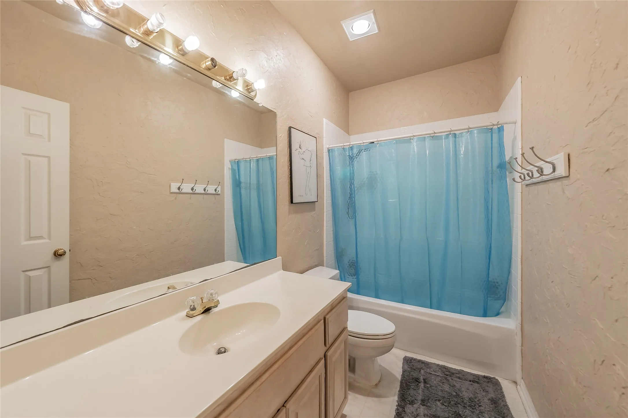 Single vanity with integrated sink, full-width mirror, and overhead strip lighting