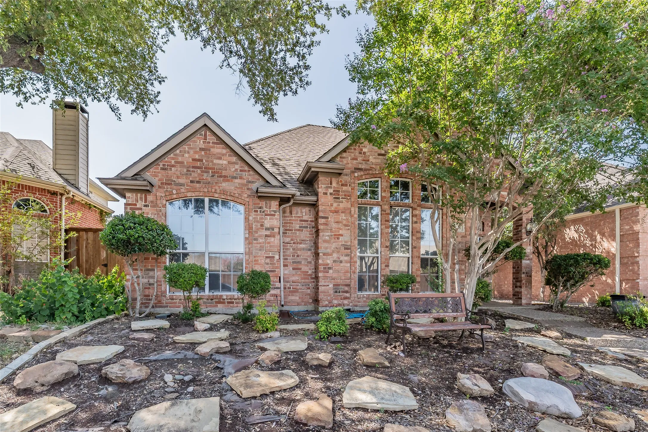 Brick facade with arched windows, gabled roofline, and established landscaping
