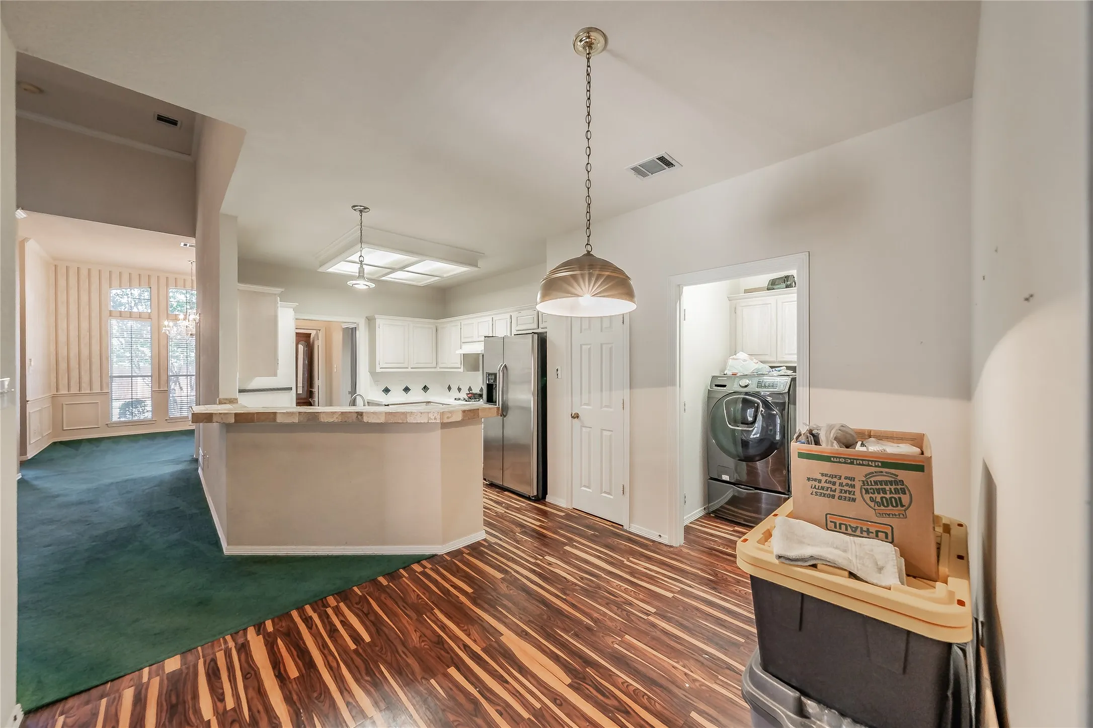 Kitchen with white cabinetry, stainless steel refrigerator, and wood-finish flooring