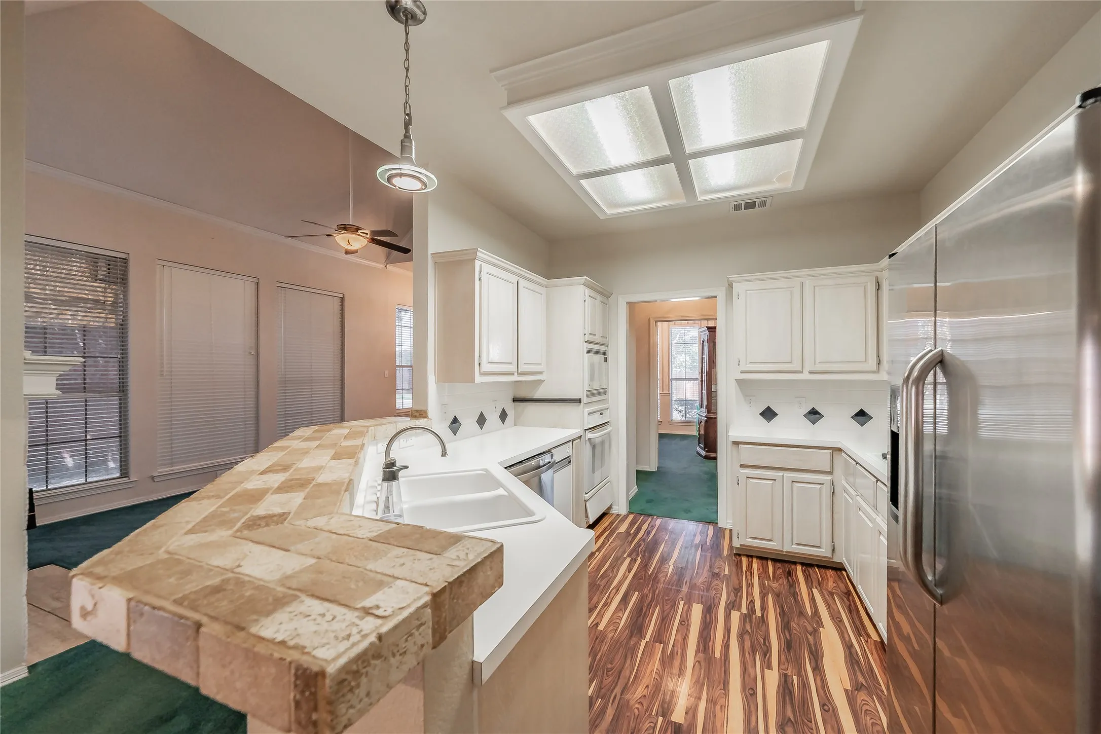 Kitchen featuring white cabinetry, white countertops, a stainless steel refrigerator, and wood-finish flooring