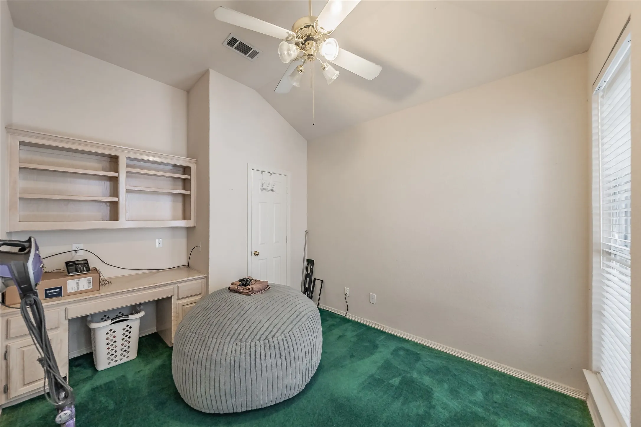 Built-in desk with overhead shelving, vaulted ceiling, ceiling fan, and window with blinds
