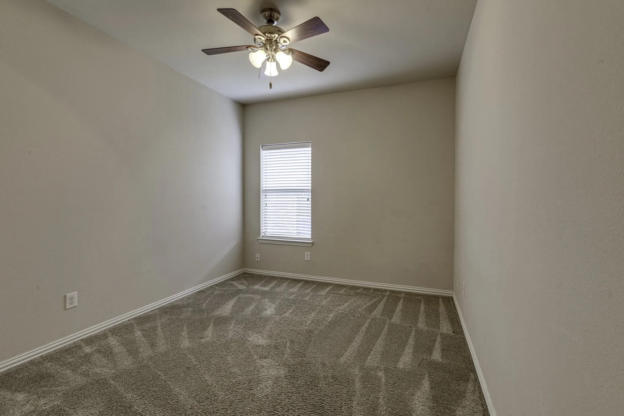 Bright secondary bedroom featuring neutral wall finishes, carpet flooring, and a ceiling fan with integrated lighting
