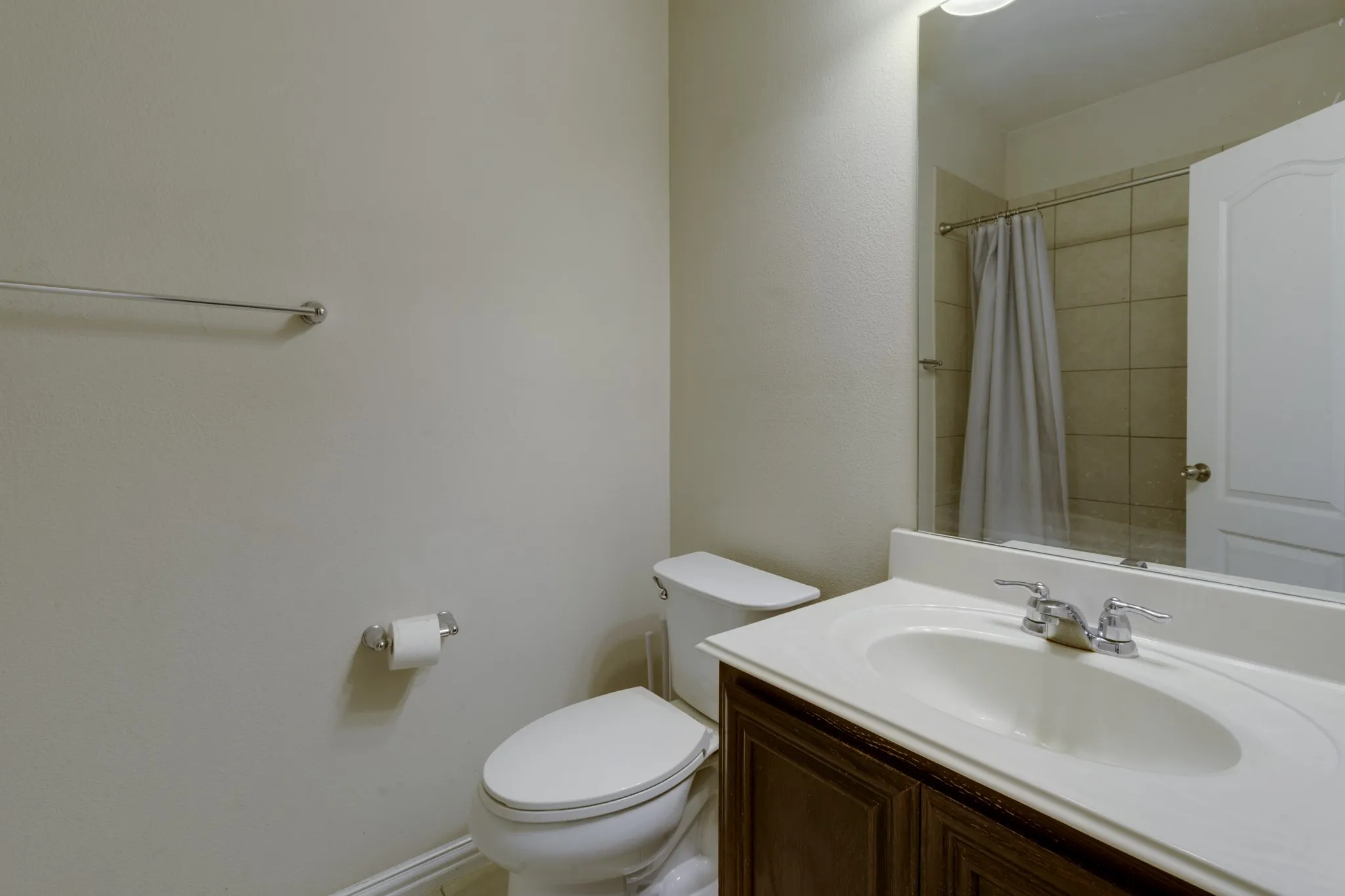 Bathroom featuring a wood-finish vanity with white countertop, undermount sink, and chrome faucet