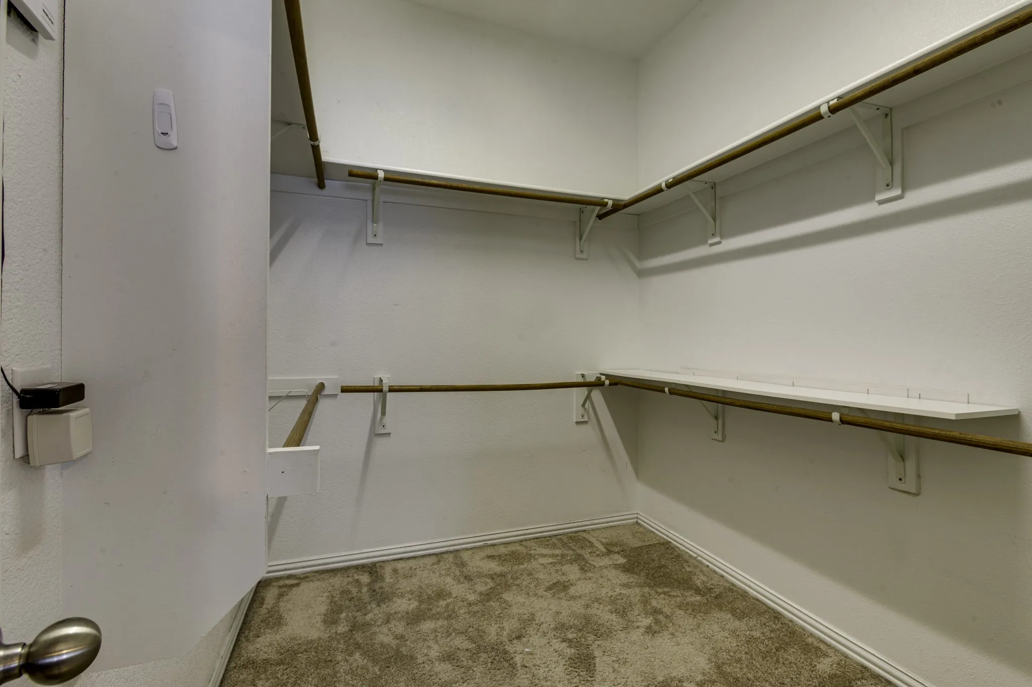 Master walk-in closet featuring white painted walls and shelving, with metal hanging rods.