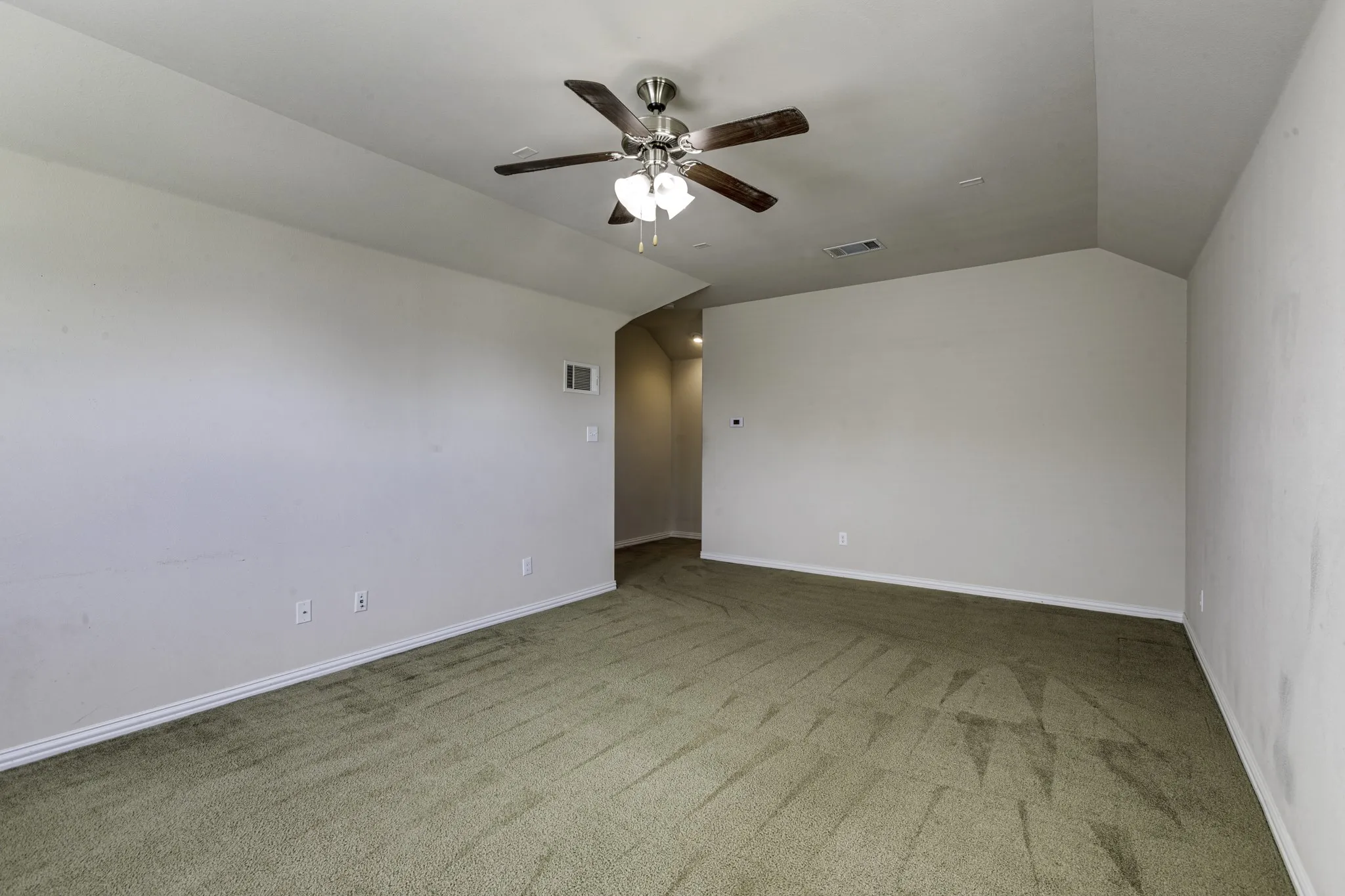 Spacious room featuring vaulted ceilings, ceiling fan, and carpeted flooring