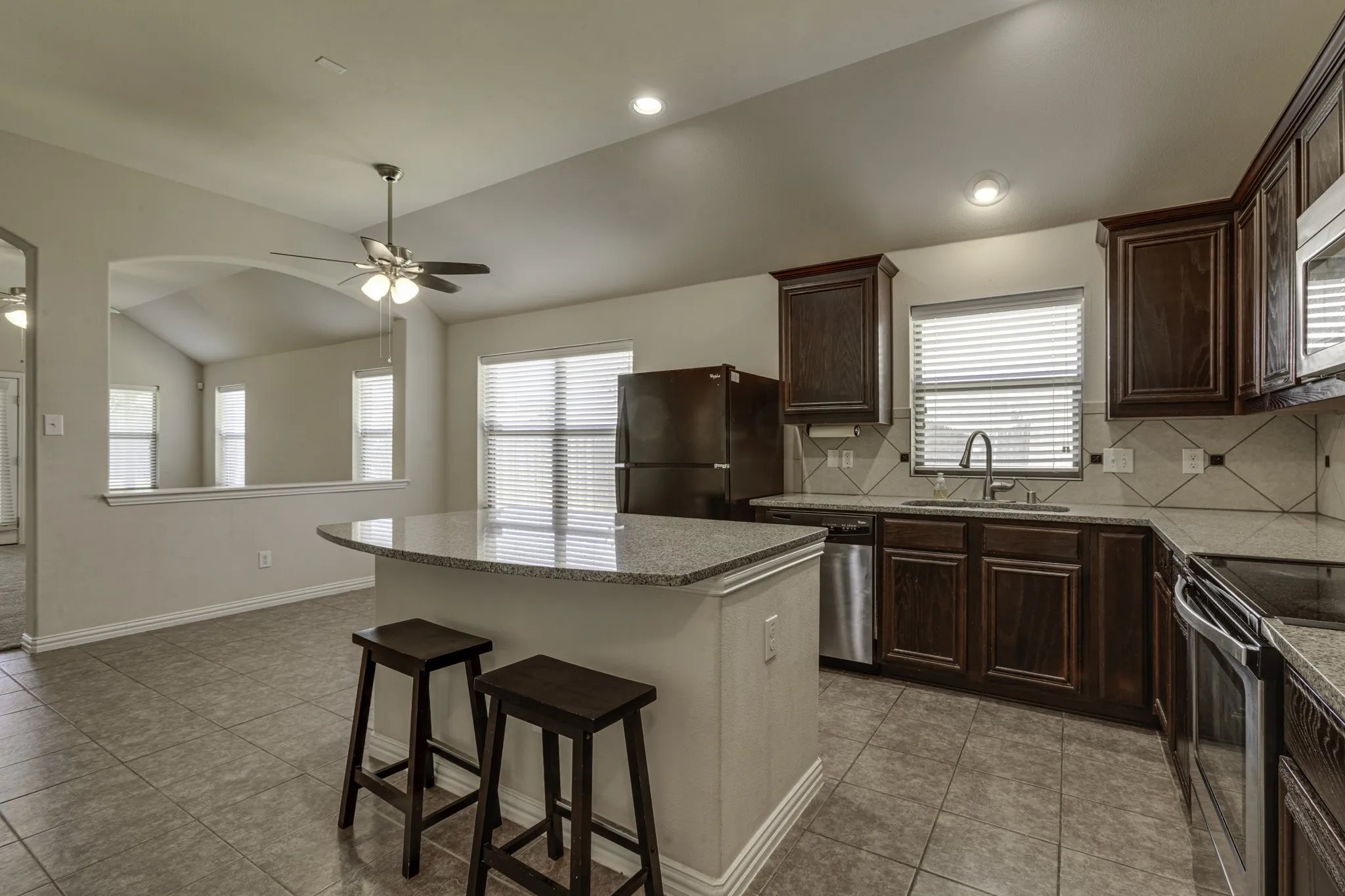 Kitchen featuring dark wood-finish cabinetry, stainless steel appliances, and a granite-topped island with seating