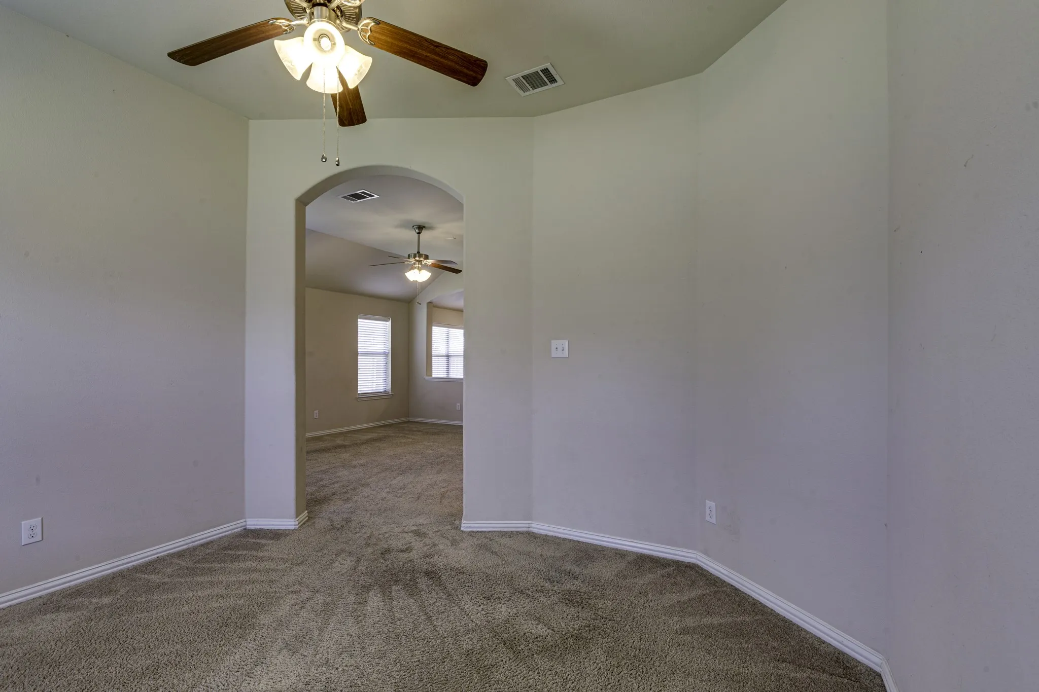 Archway entry to additional living space featuring vaulted ceilings