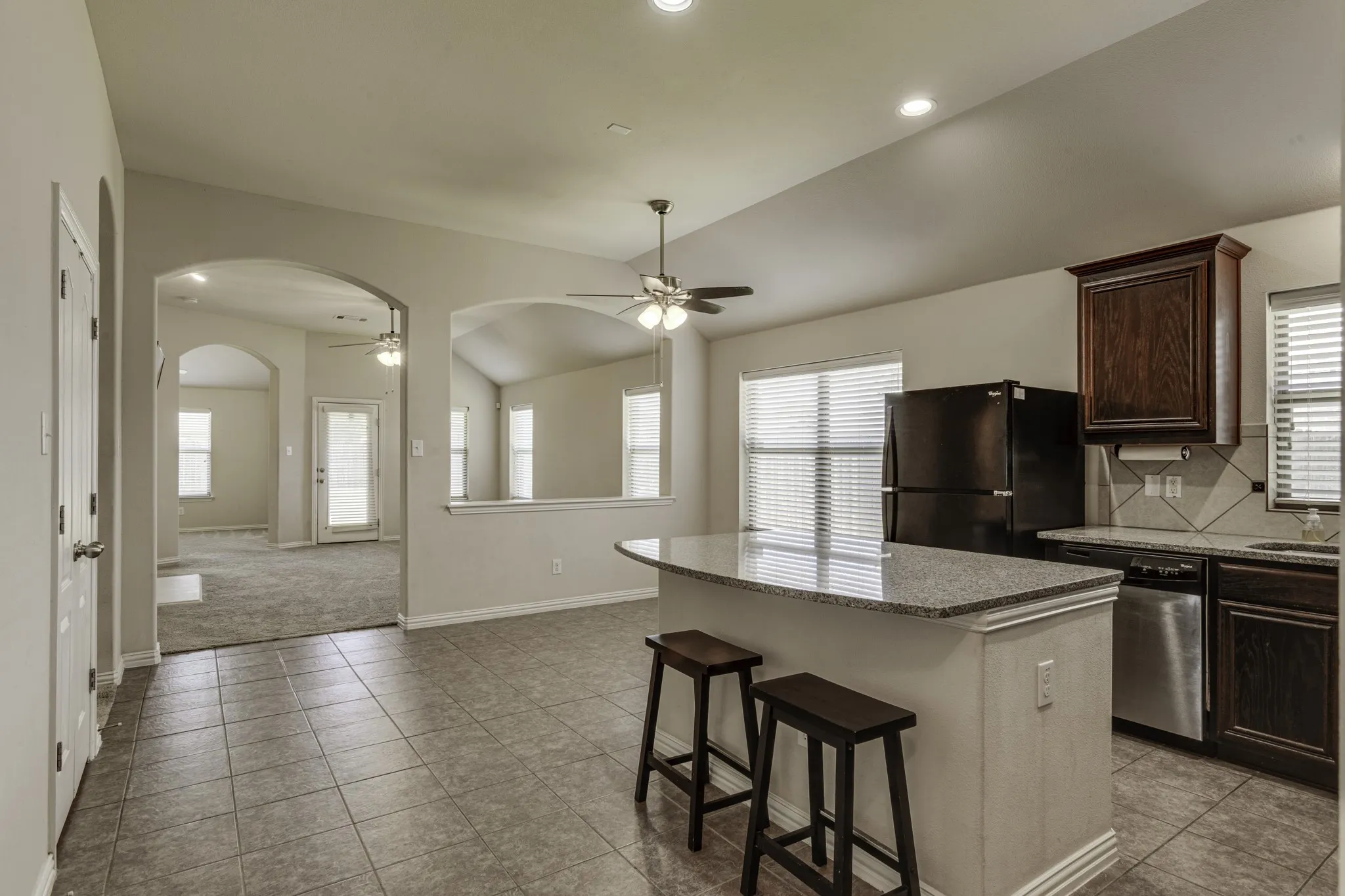 Kitchen featuring a peninsula with a granite countertop, tile floorinfamily room.