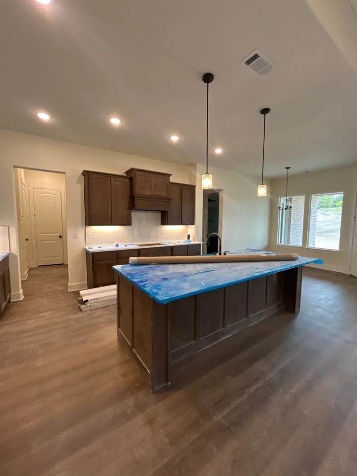 Kitchen featuring wood-finish flooring, recessed lighting, pendant lighting, and dark wood cabinetry with under-cabinet illumination