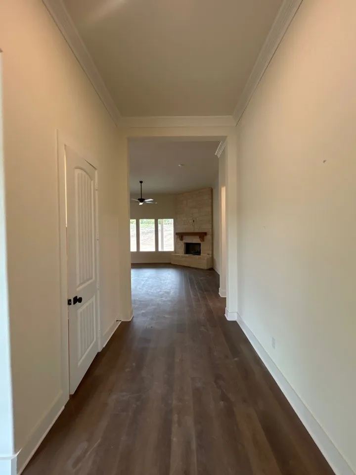 Hallway featuring dark wood-finish flooring, crisp white trim, and crown molding