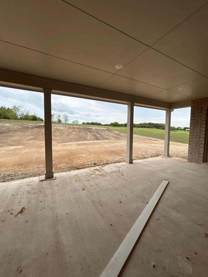 Expansive covered patio with concrete flooring, recessed lighting, and brick exterior elements