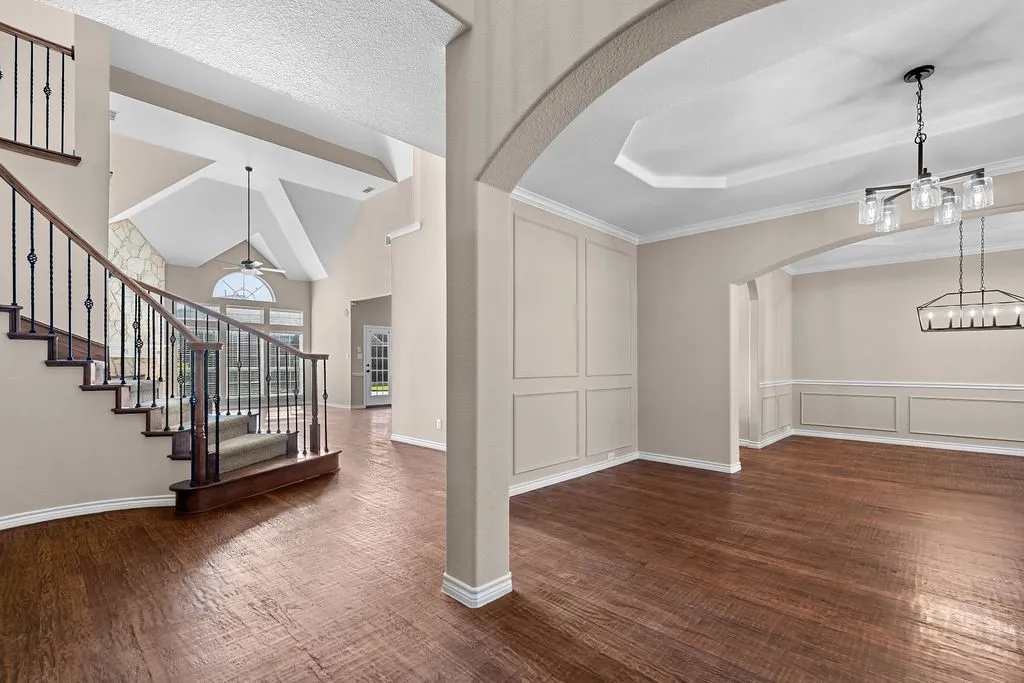 Wood-finish flooring throughout, with a decorative staircase featuring wrought iron balusters
