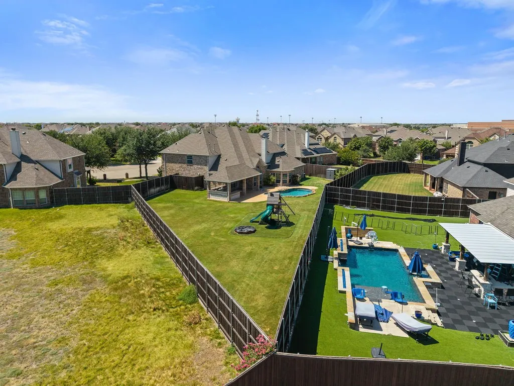 Expansive backyard featuring two swimming pools, a covered patio, and artificial turf