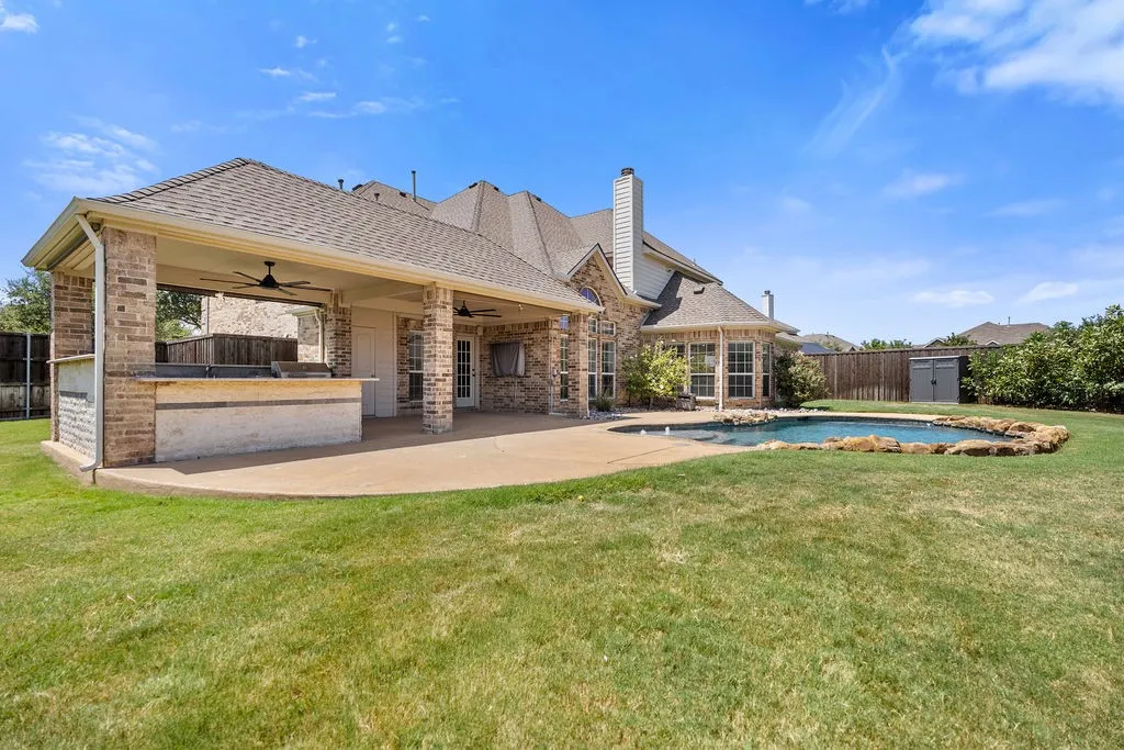 Spacious covered patio with ceiling fans, an outdoor kitchen, and a built-in swimming pool