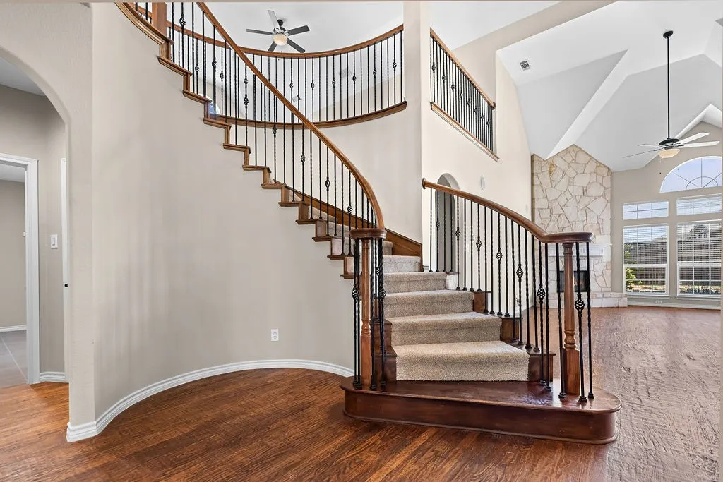 Grand curved staircase with wrought iron balusters and wood-finish handrails