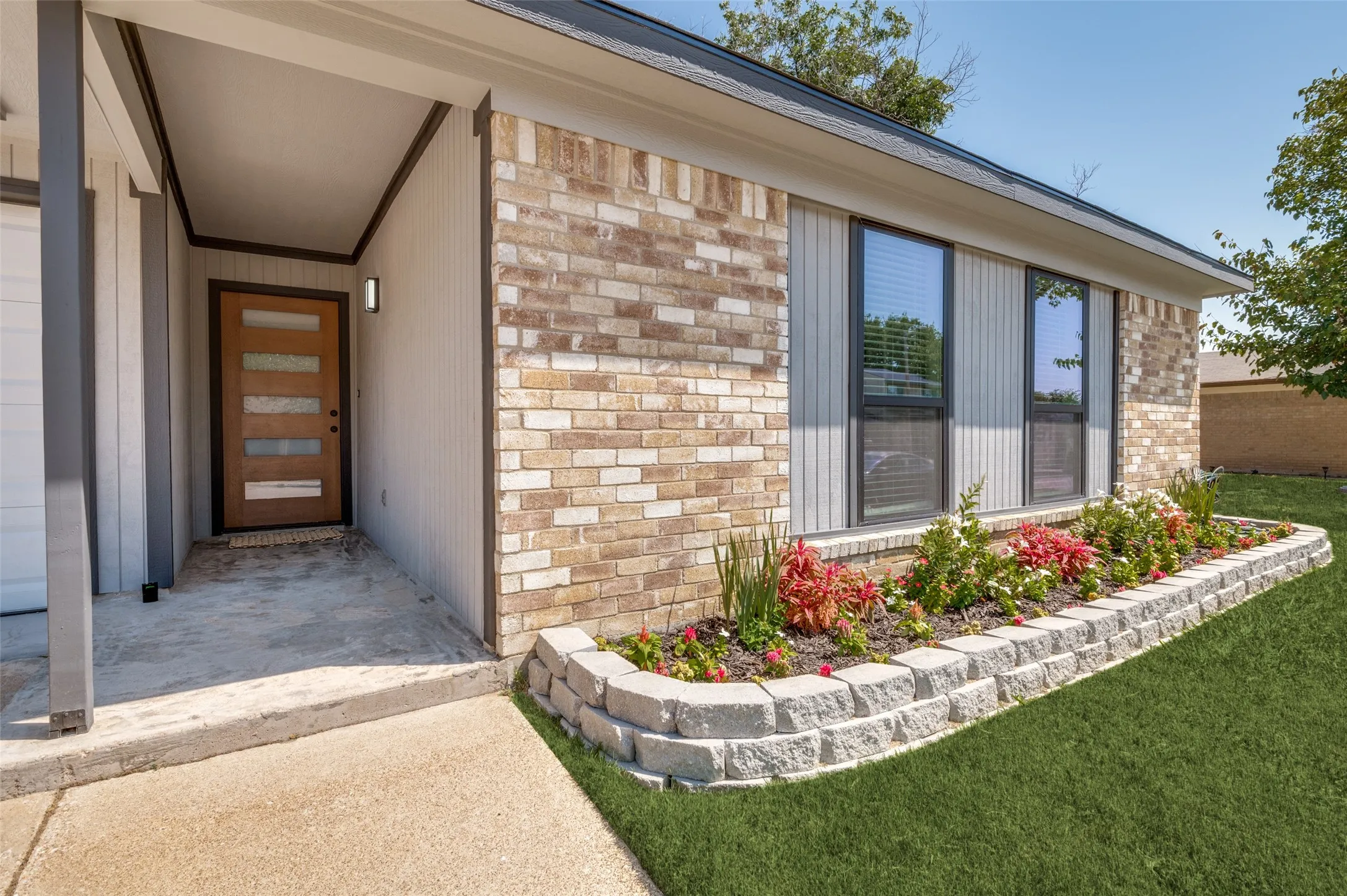 So welcoming with the covered porch and the modern wood entry door!  Not to mention the beautiful landscaping!