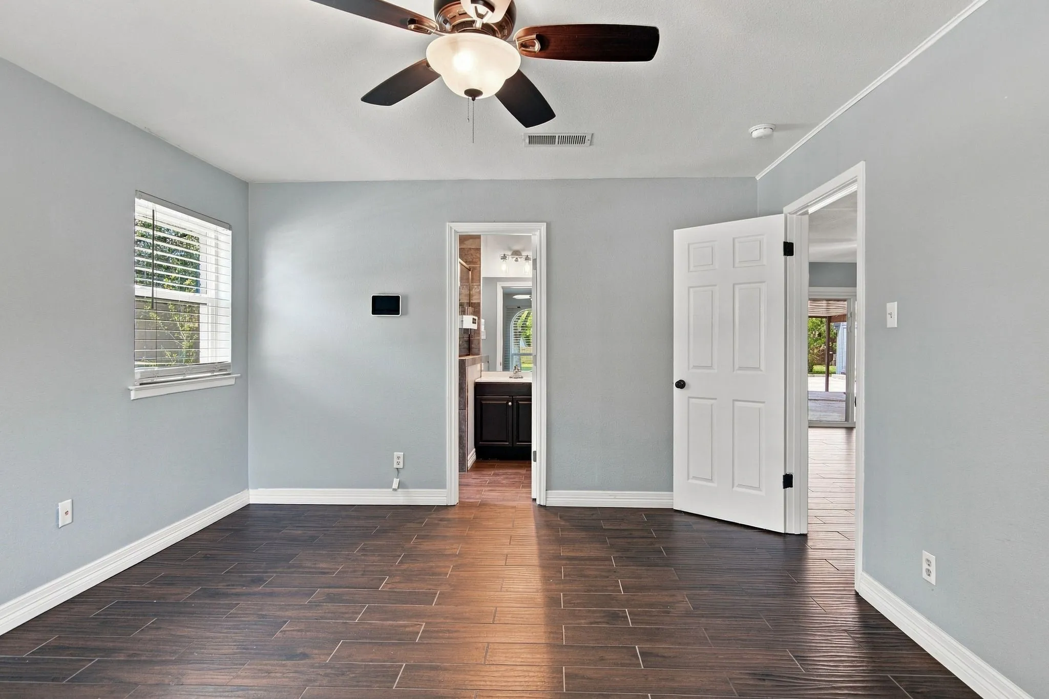 Wood-finish tile flooring, ceiling fan with light fixture, window with blinds, and white trim