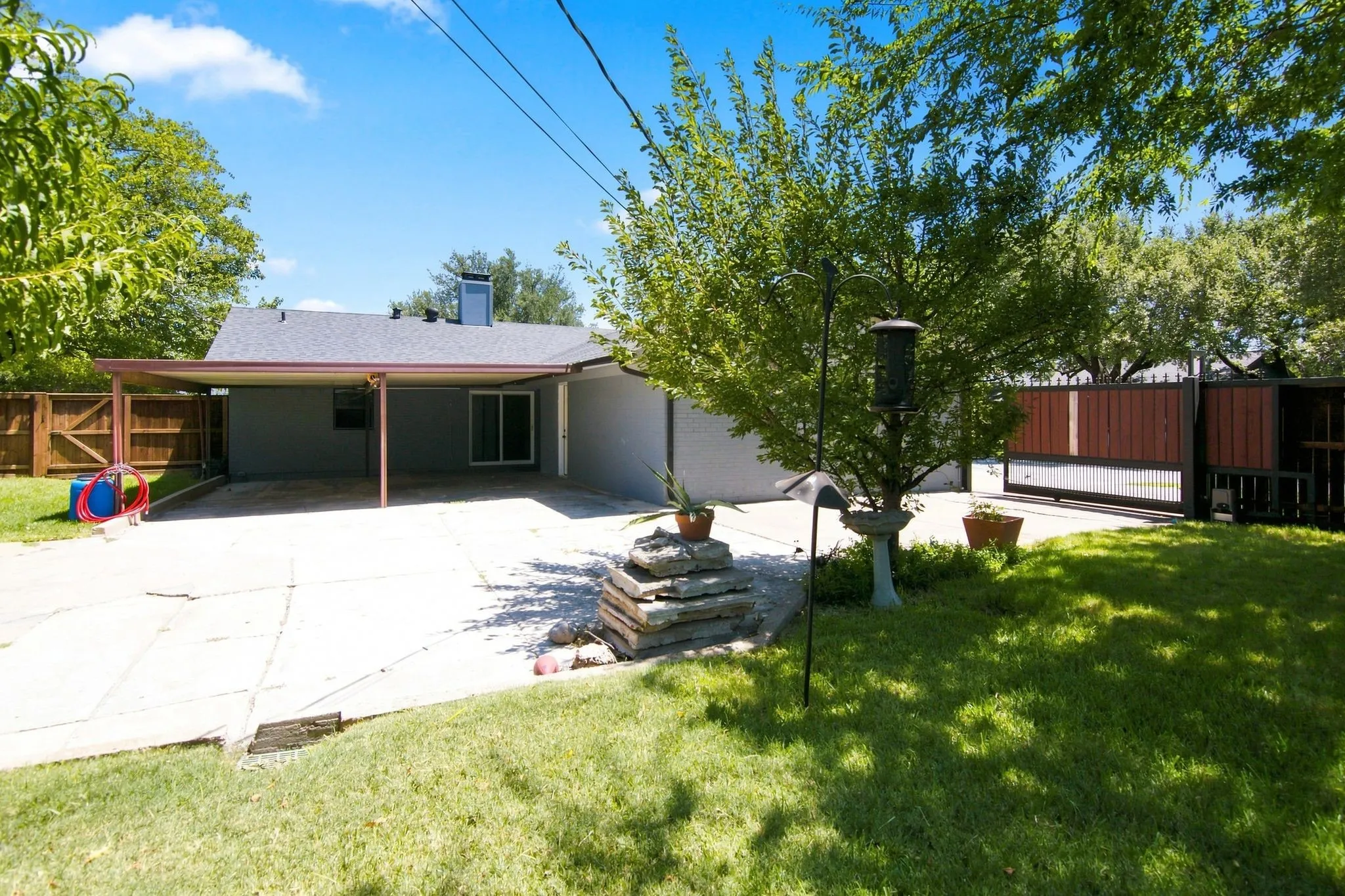 Expansive paved patio with an attached covered carport and electric gate