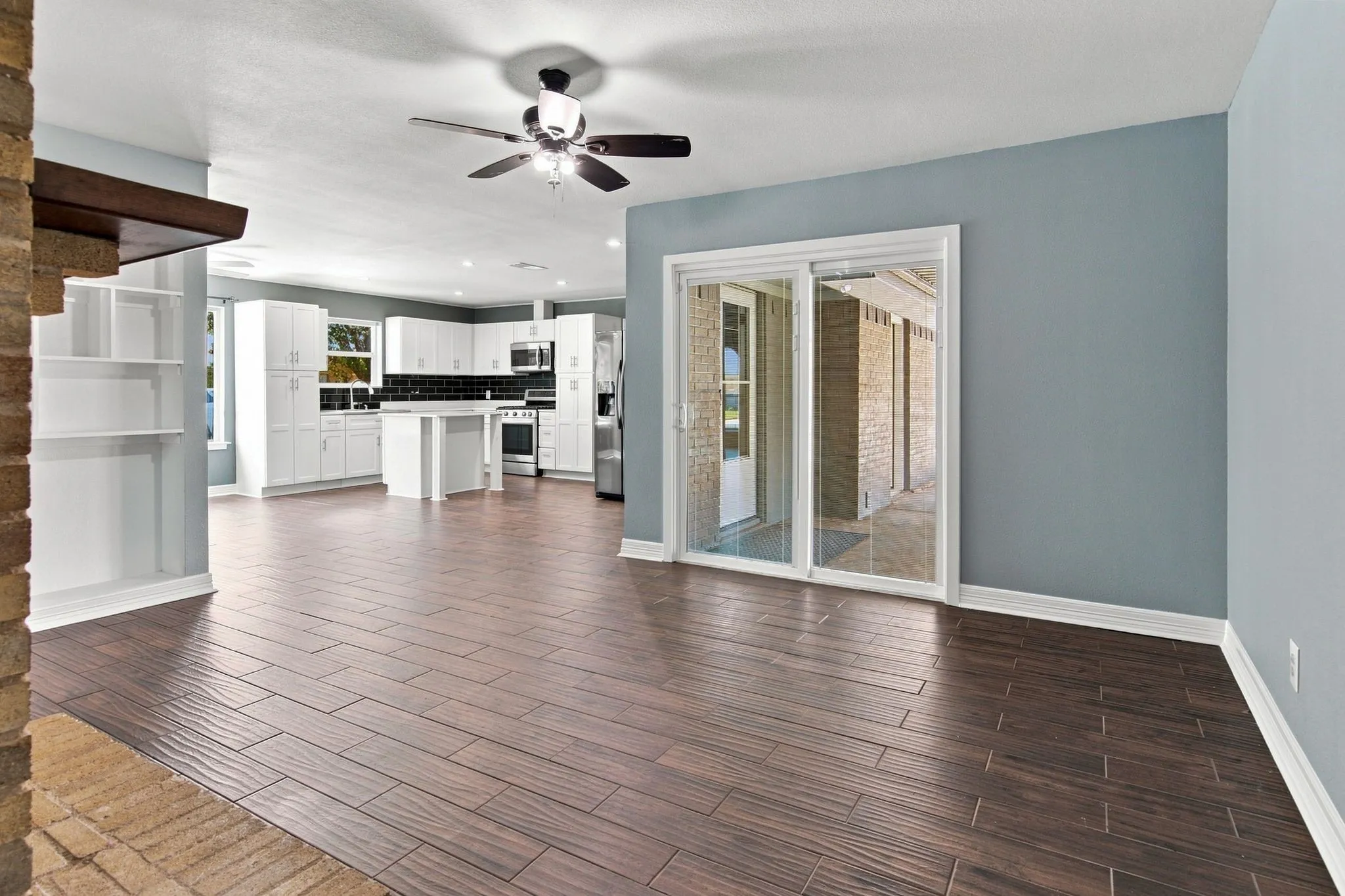 Open-concept living area with wood-finish tile flooring, recessed lighting, and a ceiling fan