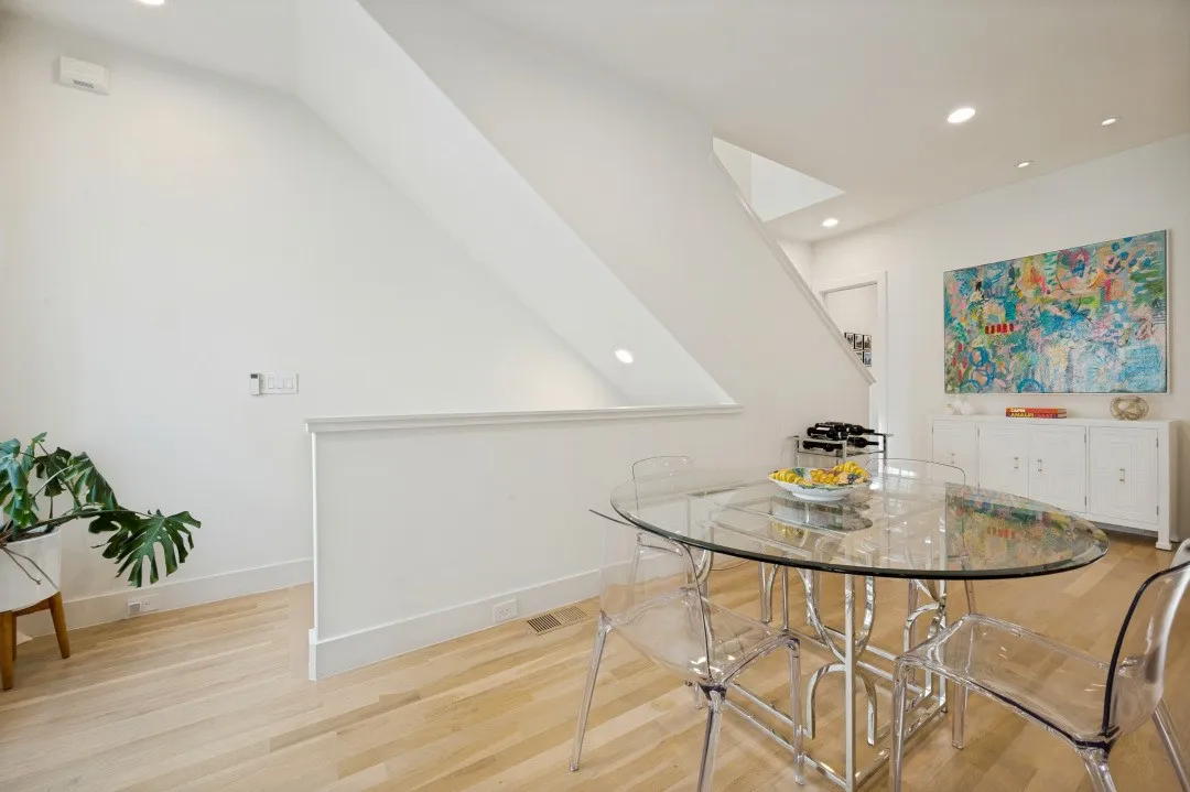 Light wood-finish flooring, recessed ceiling lighting, and a white built-in console