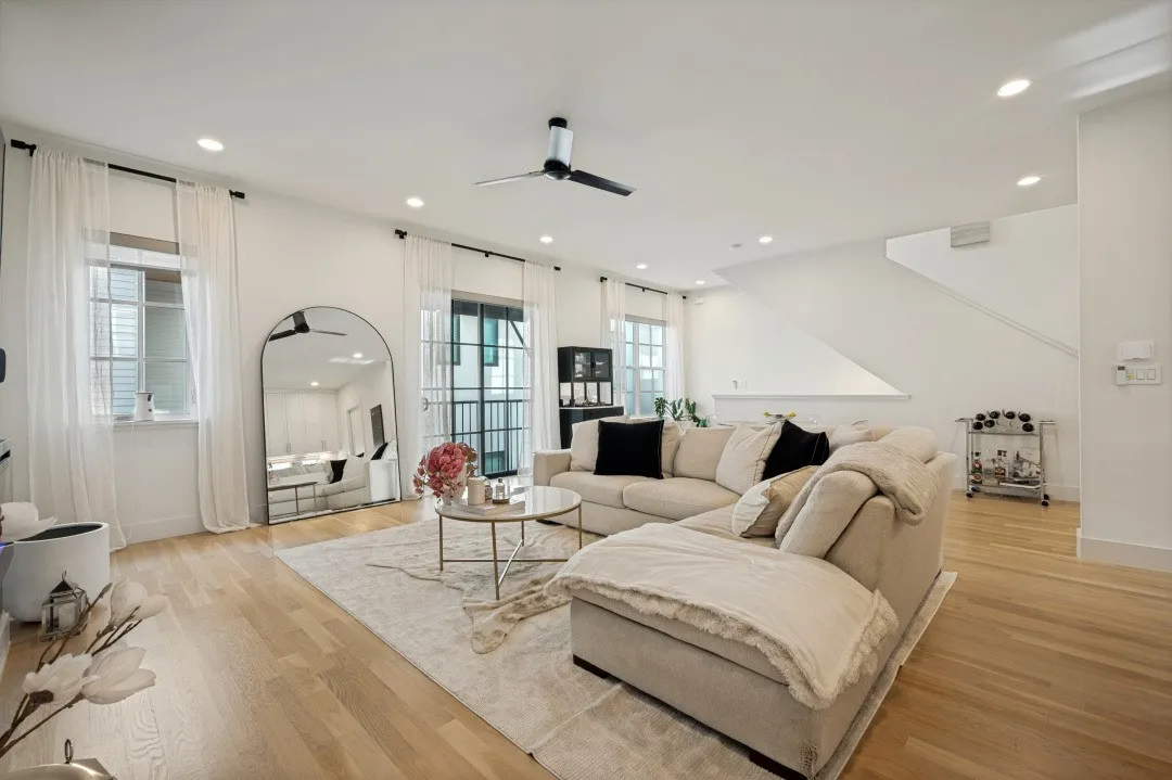 Recessed lighting, light wood-finish flooring, staircase, ceiling fan, and large windows with transom details