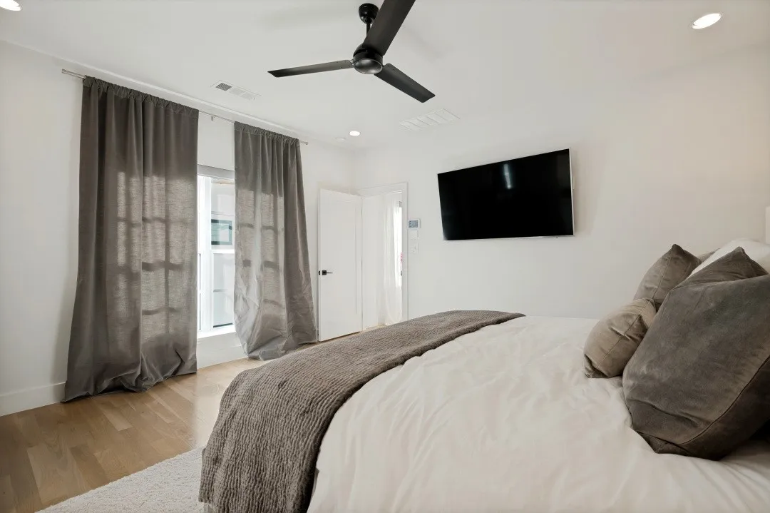 Recessed ceiling lighting, a contemporary ceiling fan, and wood-finish flooring