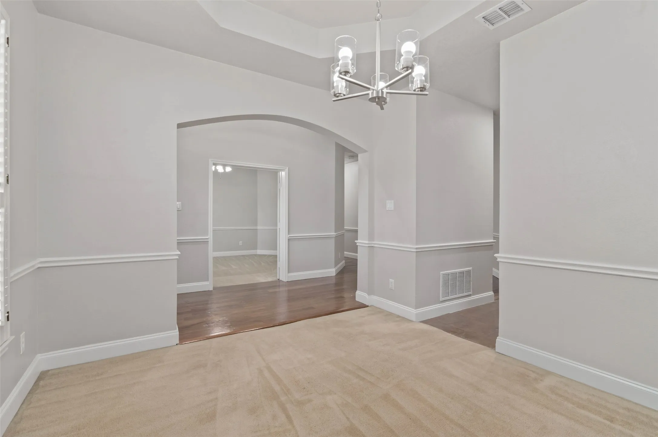 Carpeted dining area with decorative lighting and plantation style shutters.