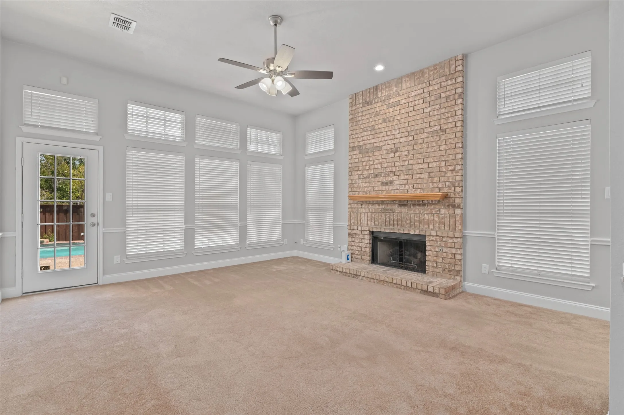 Spacious living area with plenty of windows, gas fireplace and back door opening to the beautiful back yard and pool area.