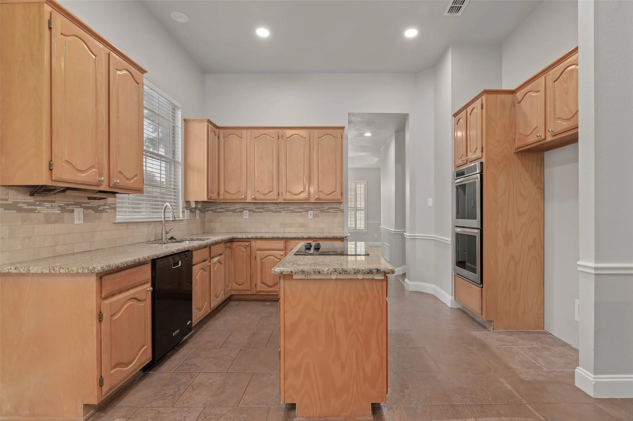 Beautiful kitchen with granite countertops, decorative backsplash and double oven.
