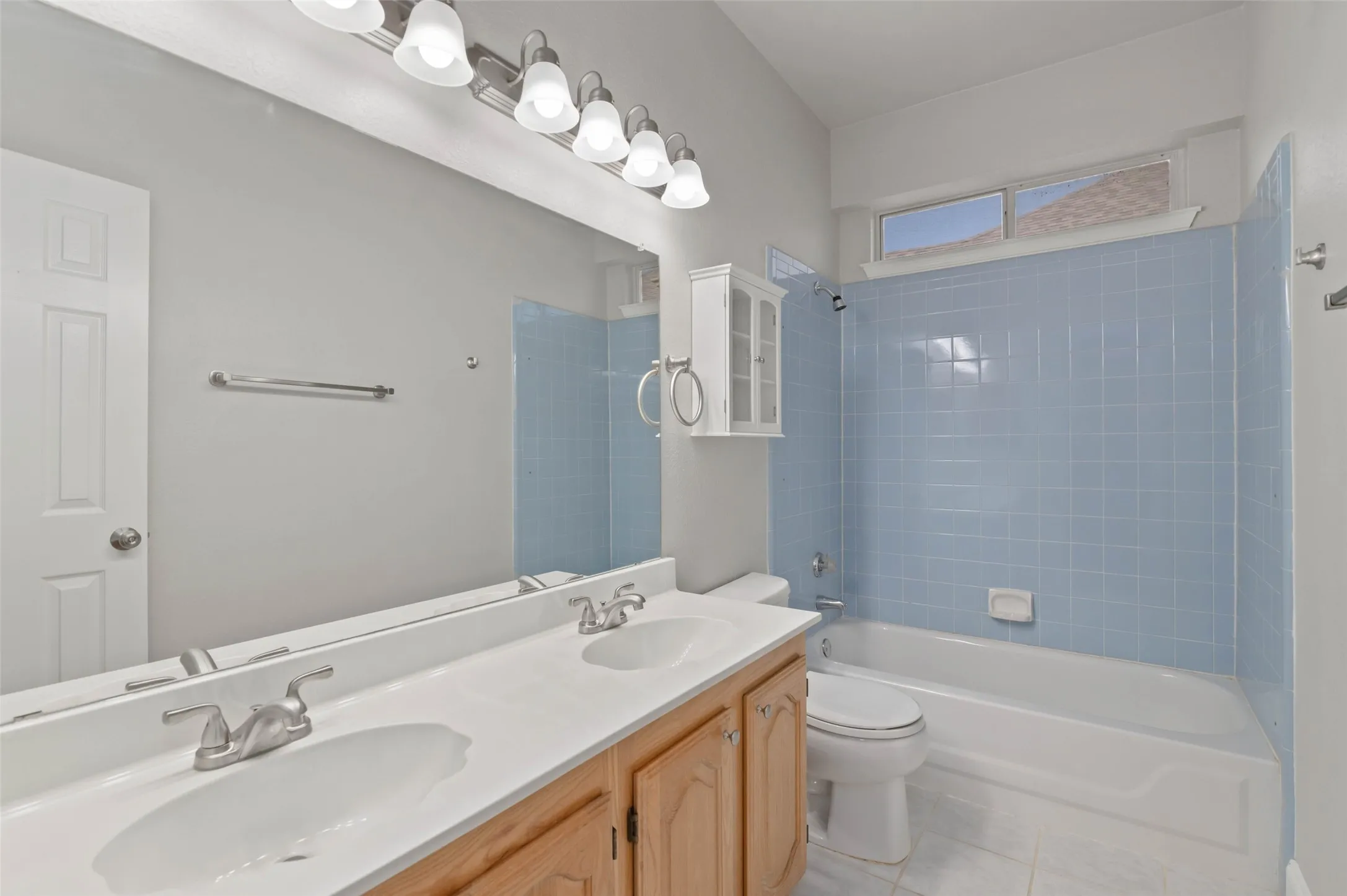Bathroom with decorative tile and a dual sink vanity.