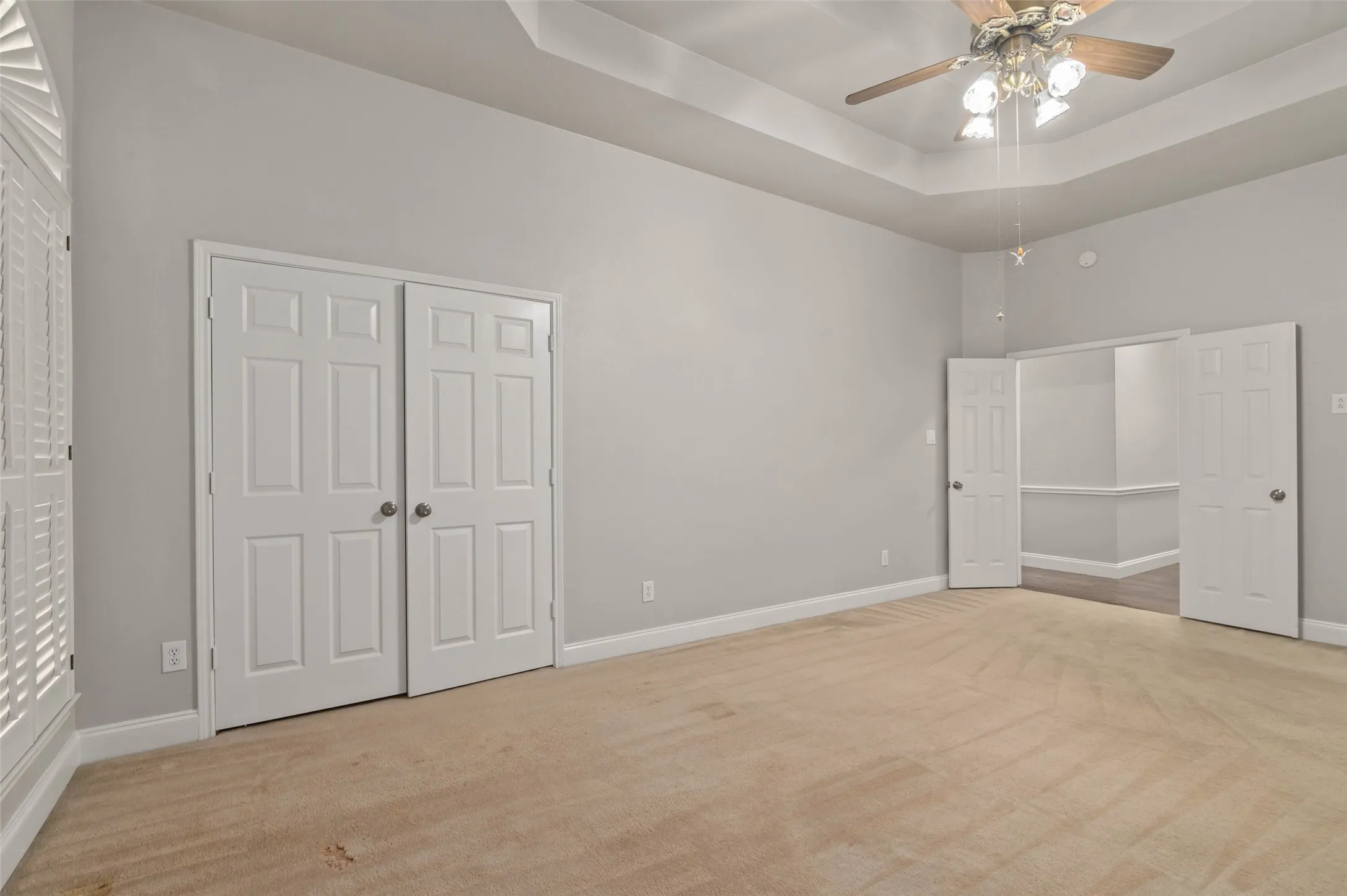 Huge primary bedroom with carpeted flooring, ceiling fan and large picture windows.