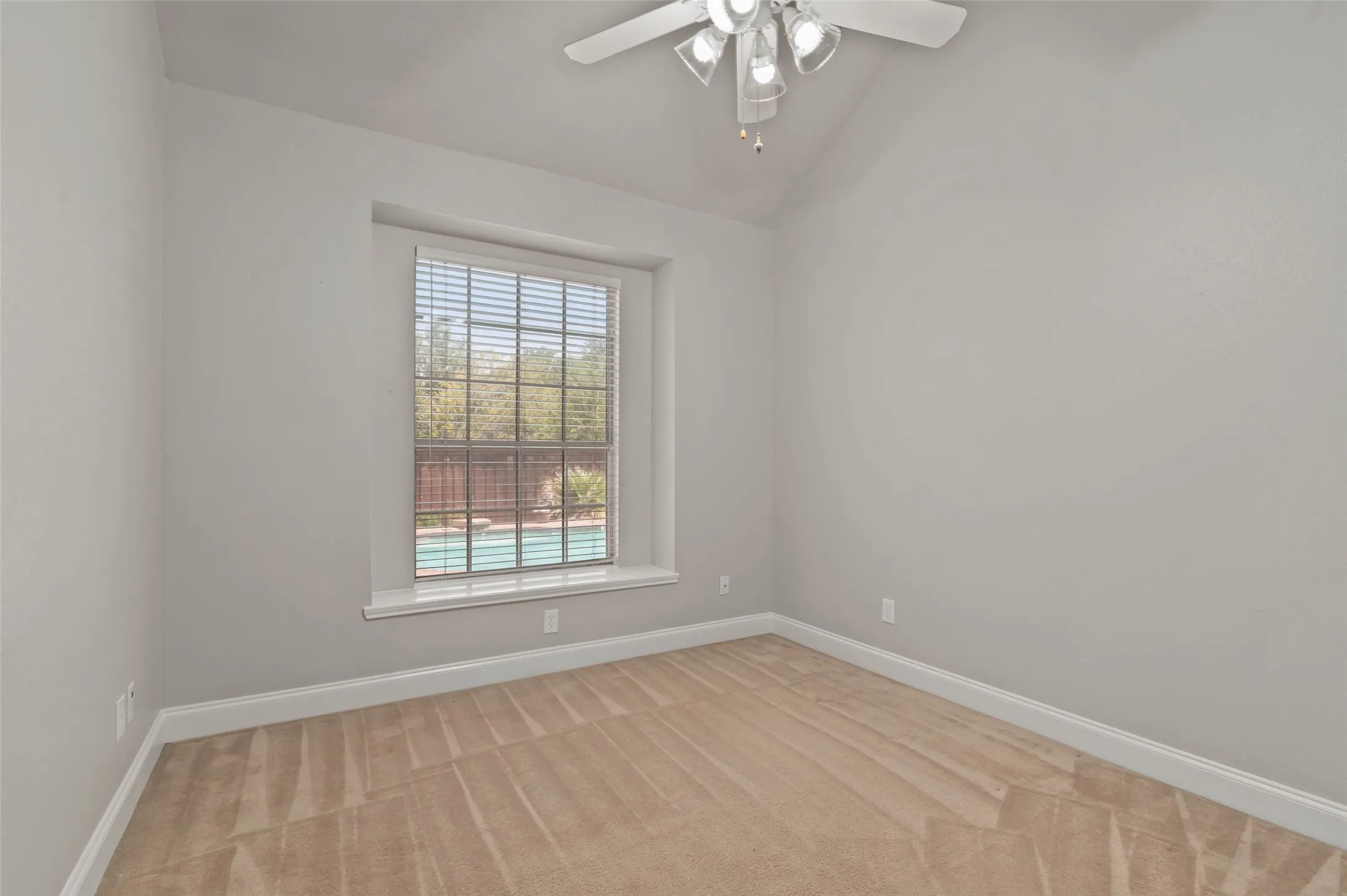 Secondary bedroom with carpeted flooring and ceiling fan with a beautiful view of the pool and back yard.
