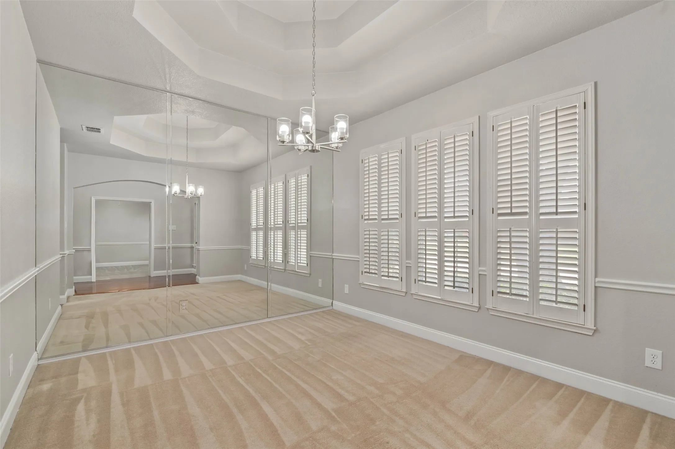 Carpeted dining area with decorative lighting and plantation style shutters.