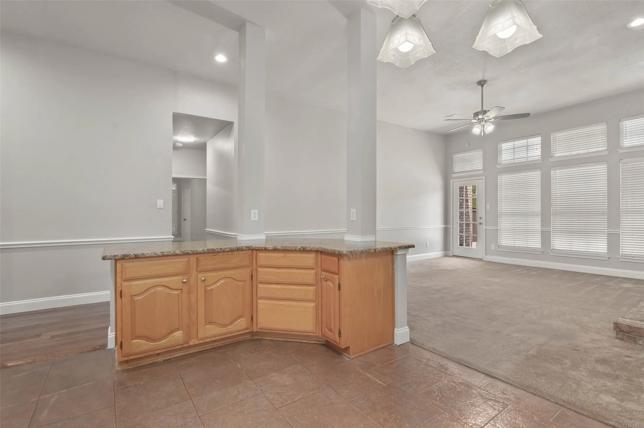 Built-in cabinetry with a stone-finish countertop, tile flooring, and broad wall-to-wall carpeting